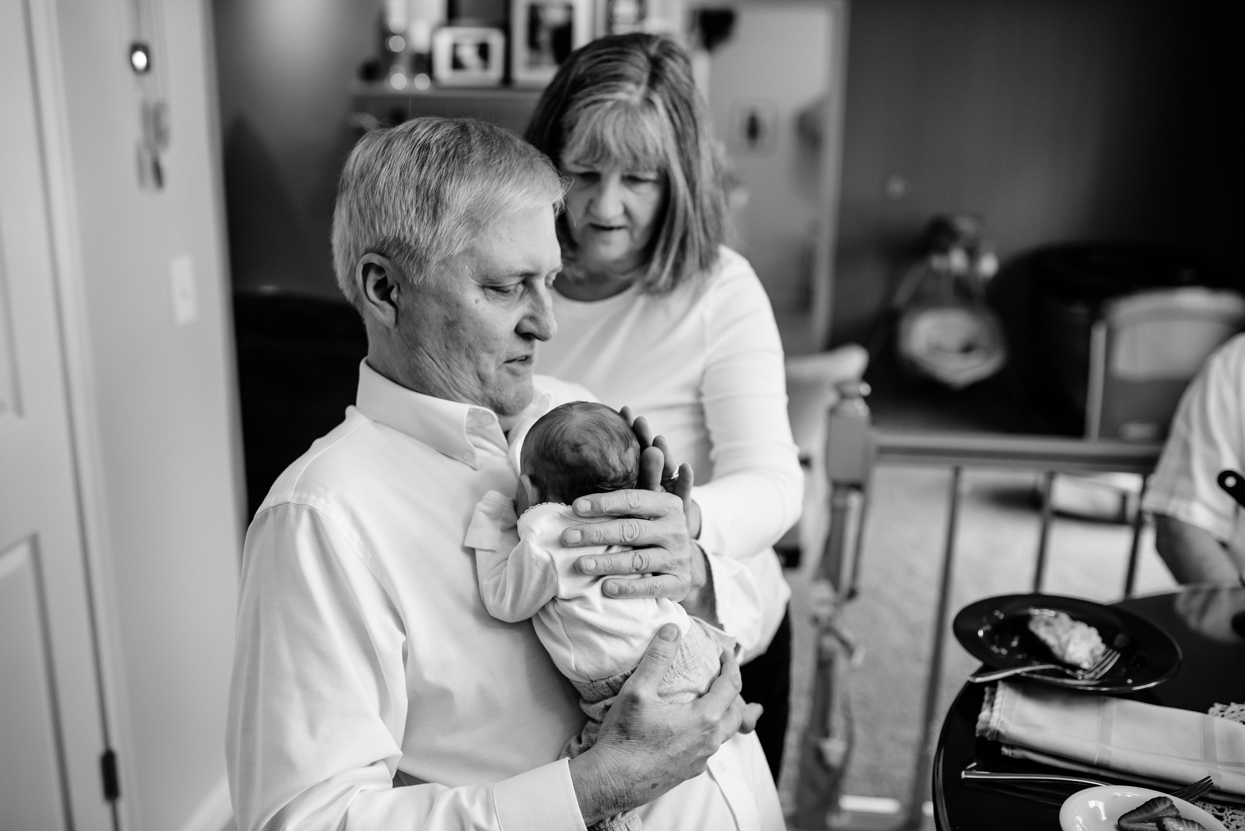 Grandparents hold and gaze at baby