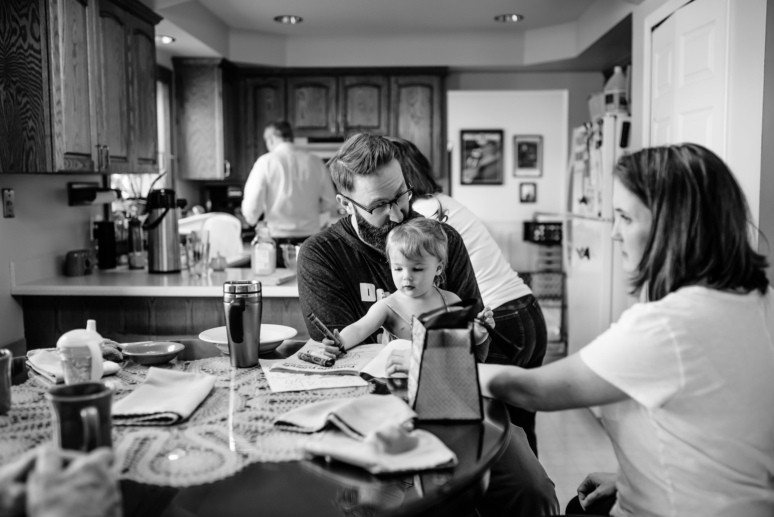 Family colors with toddler girl after breakfast at kitchen table