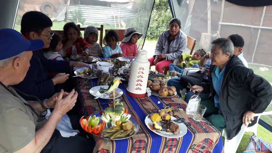 Sharing pachamnca lunch with children at the Pillaray school with customers of Valentin's Pachamama Journeys