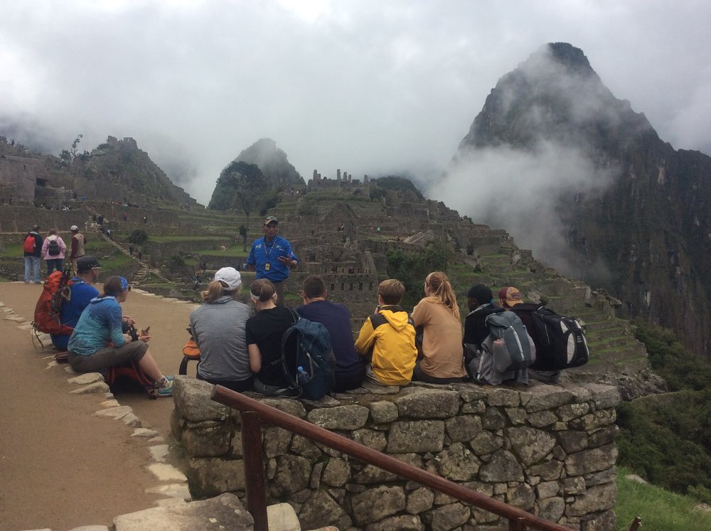 Guide and tourists ona  tour at Machu Picchu ruins, Peru.jpg