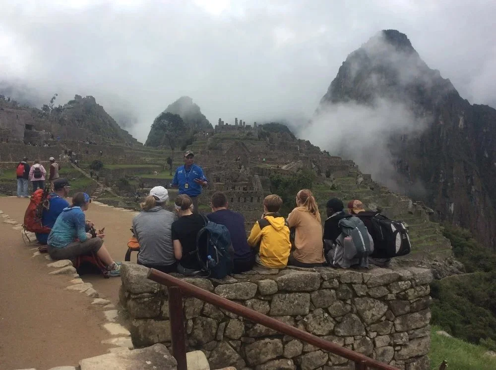 Guide and tourists on a guided tour at Machu Picchu ruins, Peru.jpg