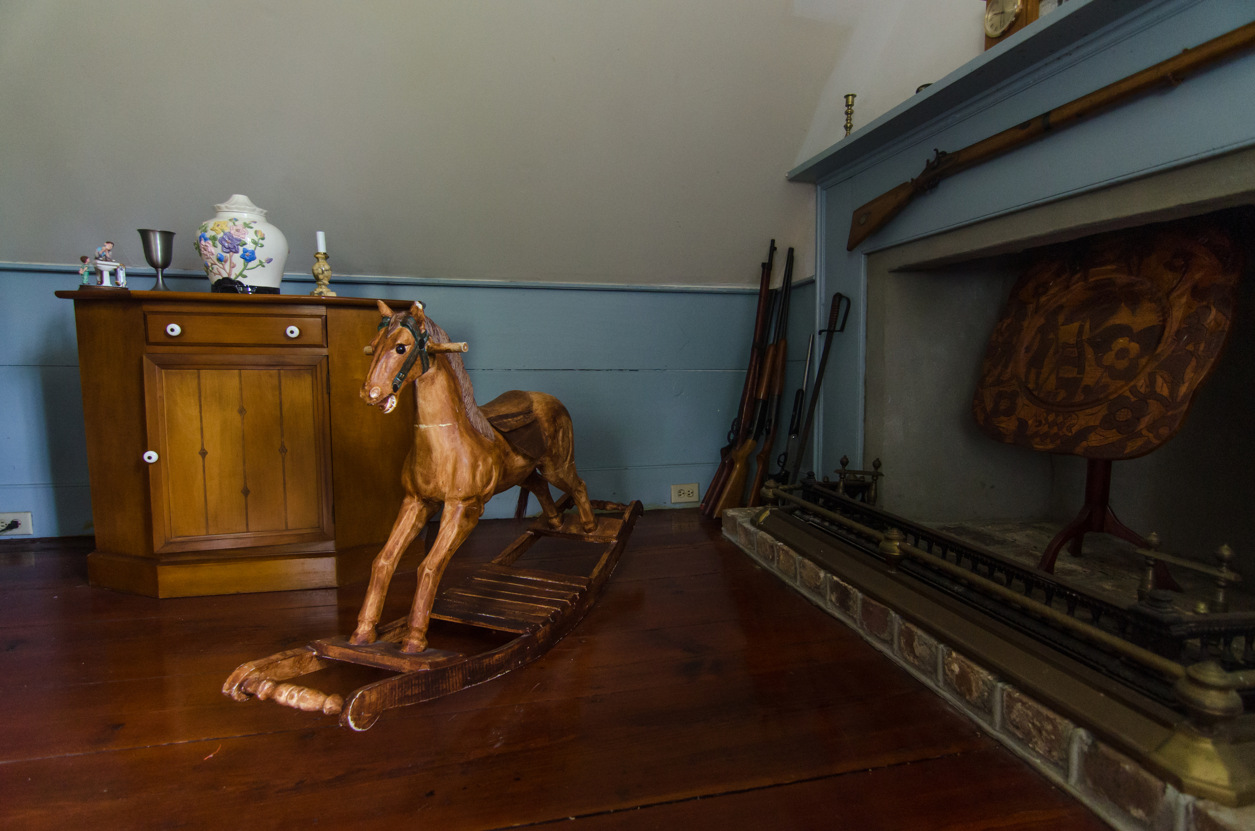 An antique horse-rocker next to a fireplace.