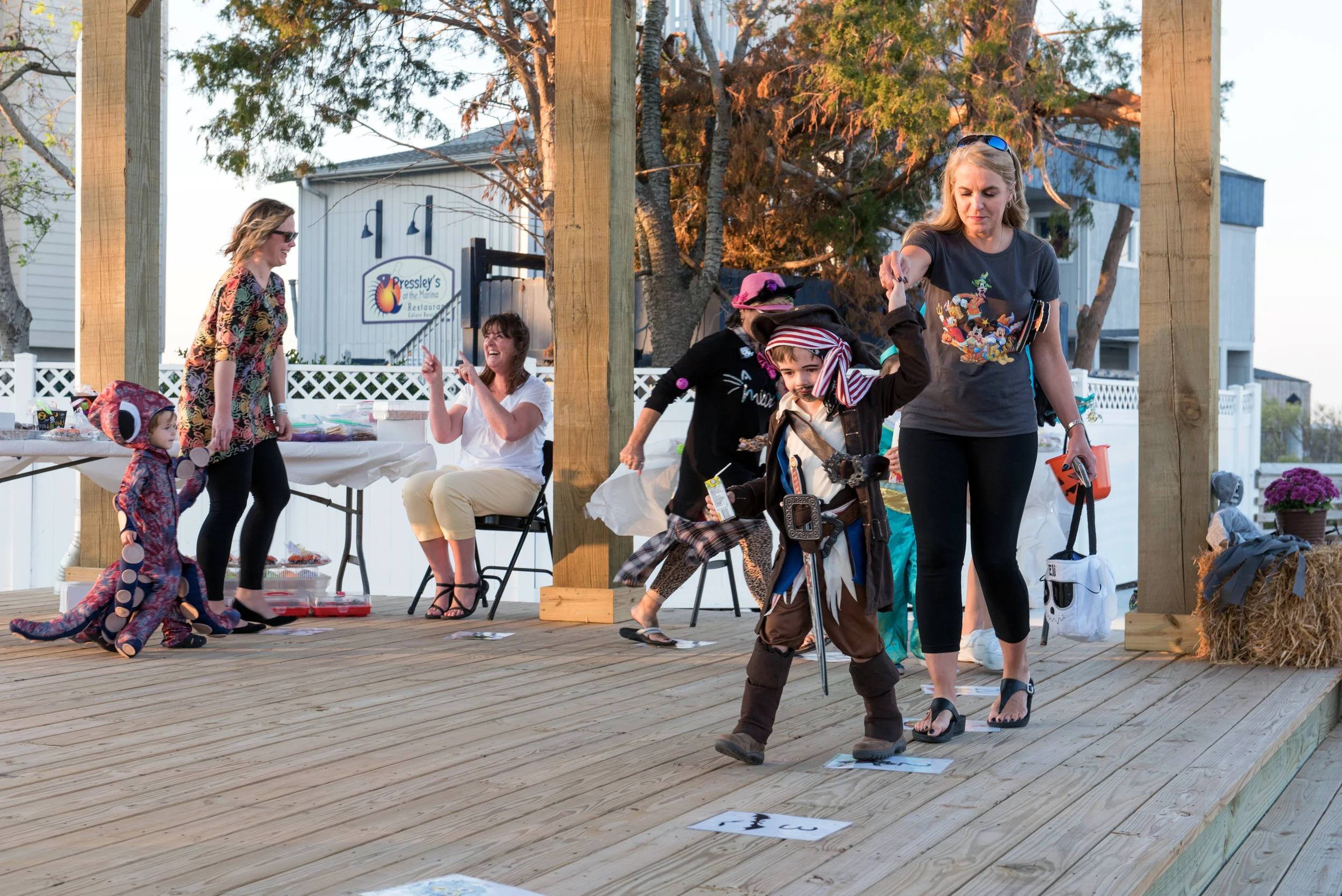 Young people in Halloween Costumes participating a cake walk with their moms.