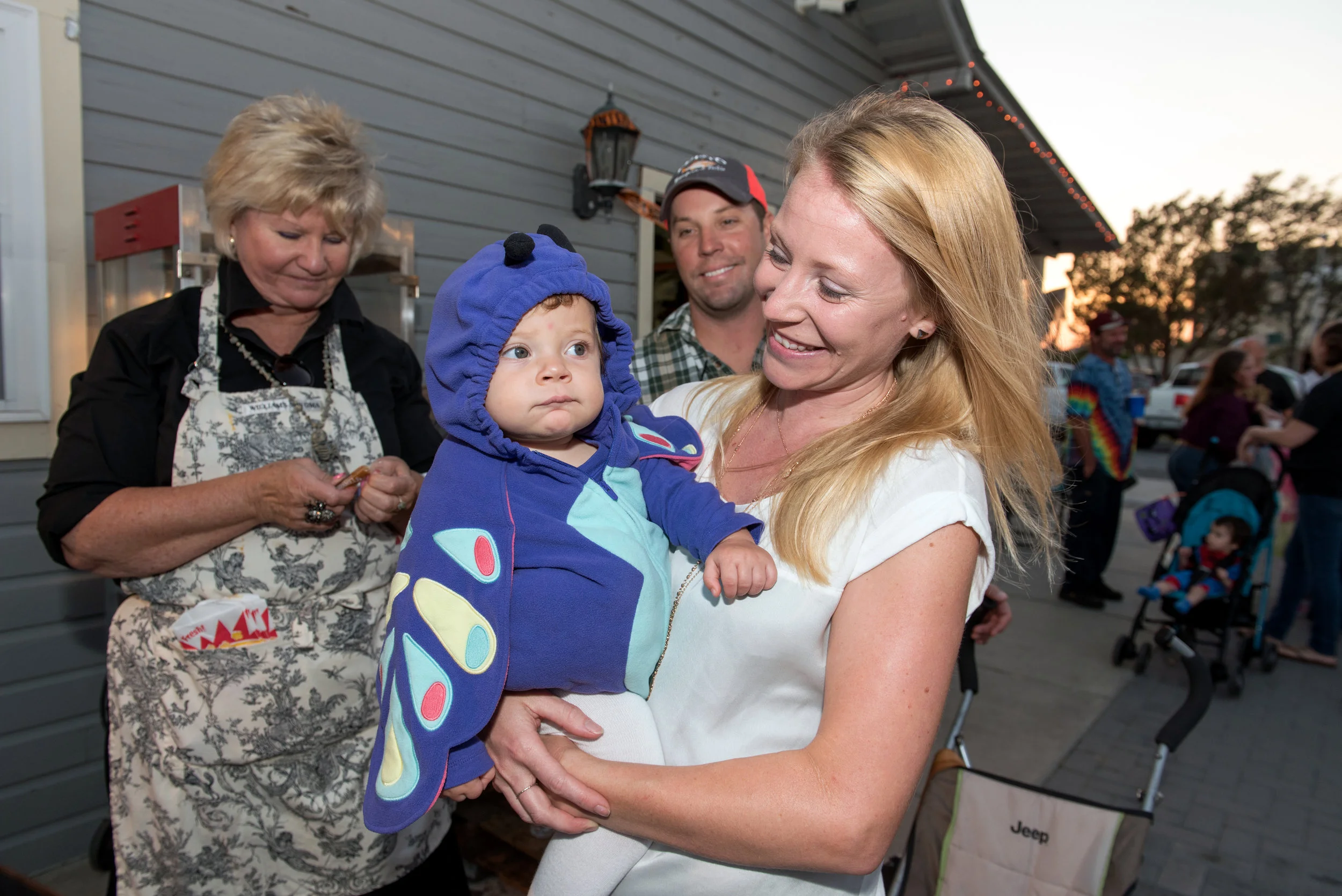 Mother holds child dressed as a butterfly at Halloween festival.