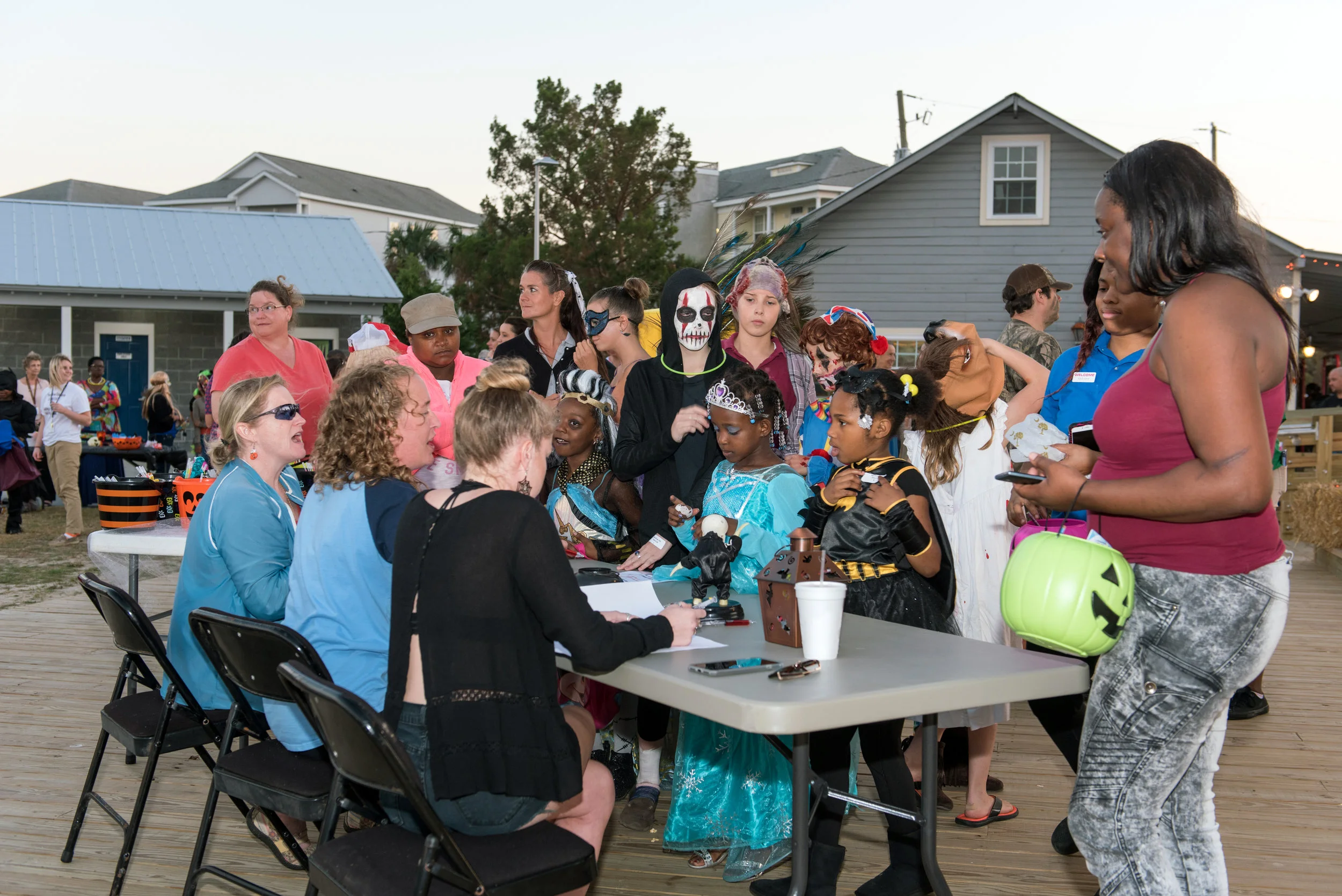 People in costumes gather around a table at Halloween Festival.