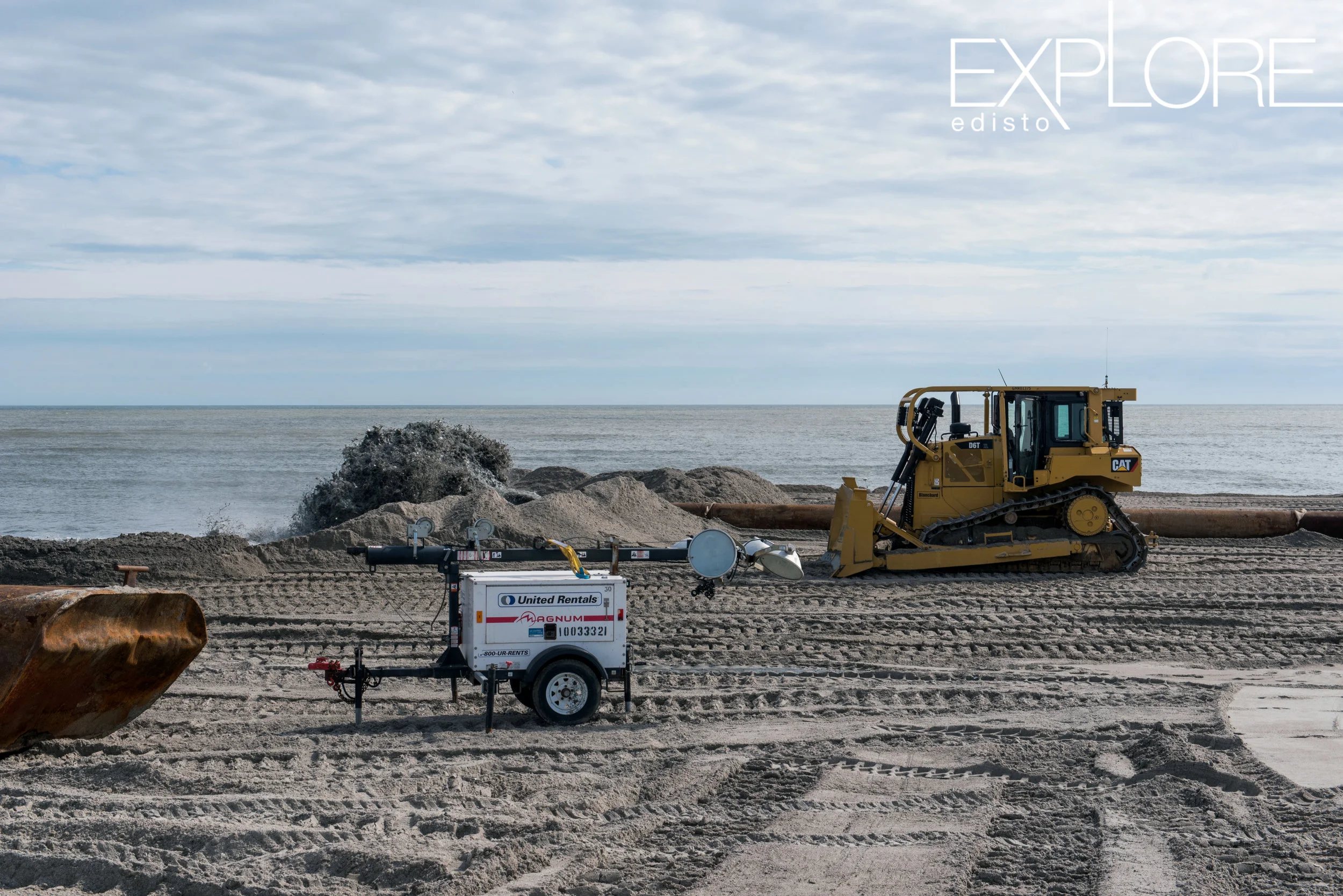 Tractor and sand being pumped onto the beach from the ocean.