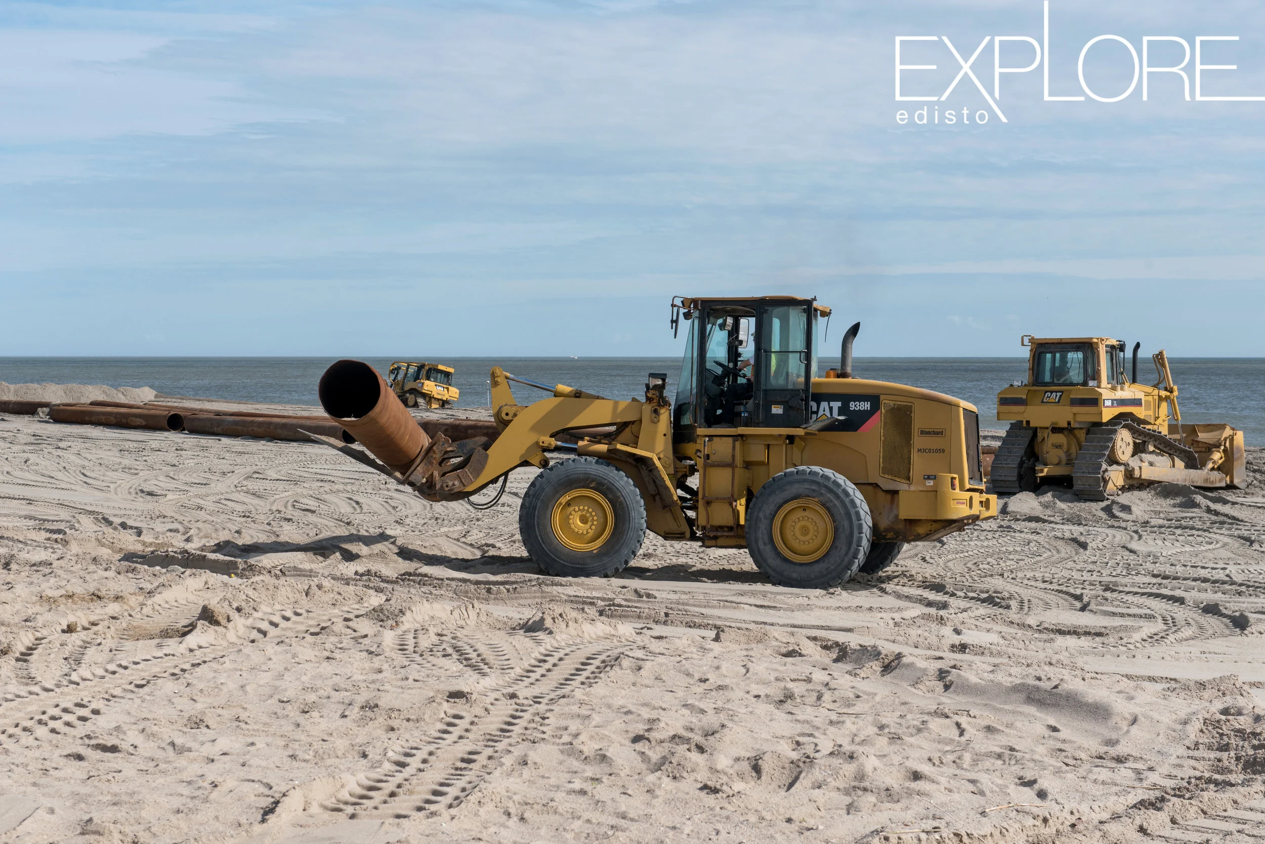 Tractor moves pipe on the beach during beach nourishment.