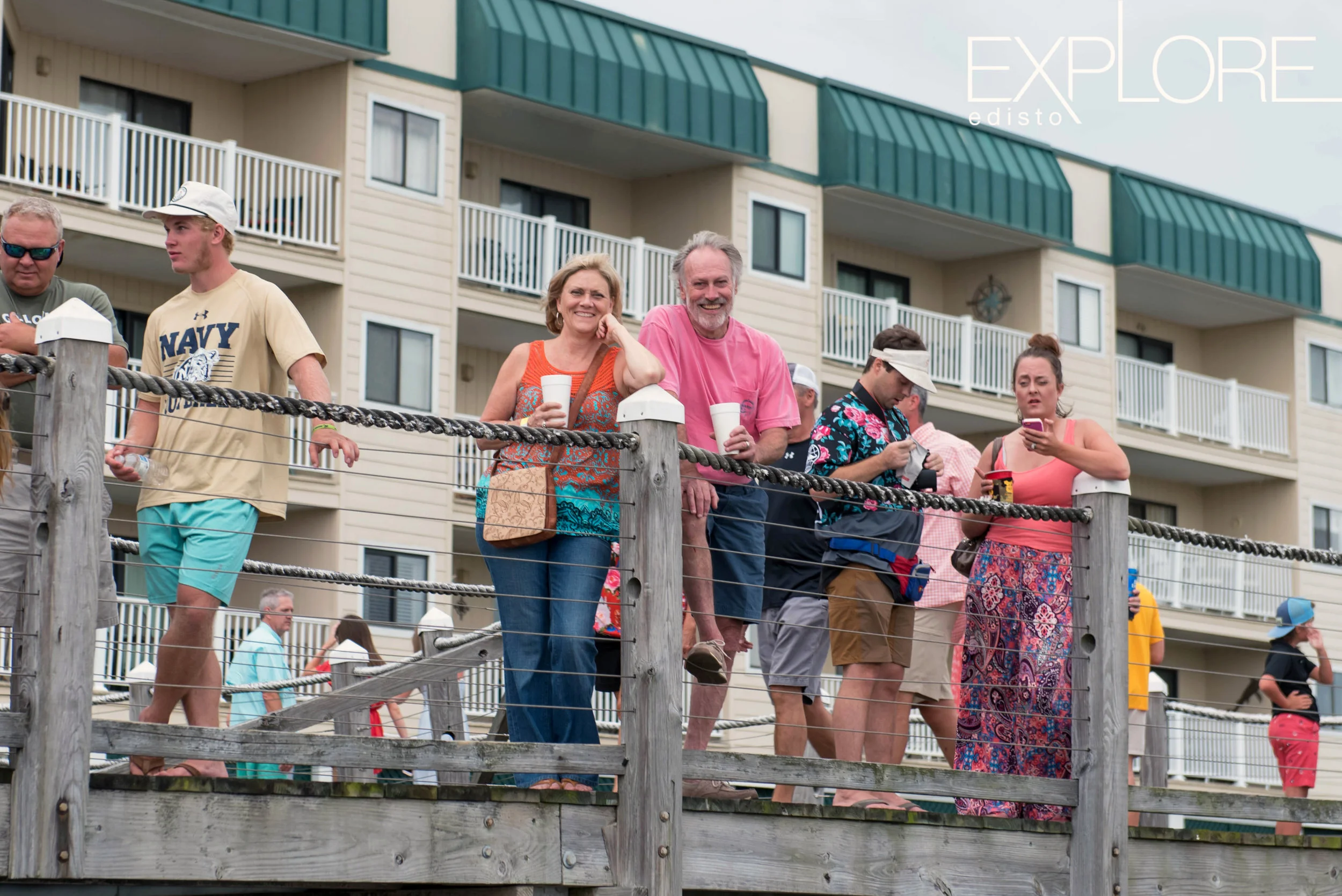 Woman in orange and man in pink pose on dock at the Marina.