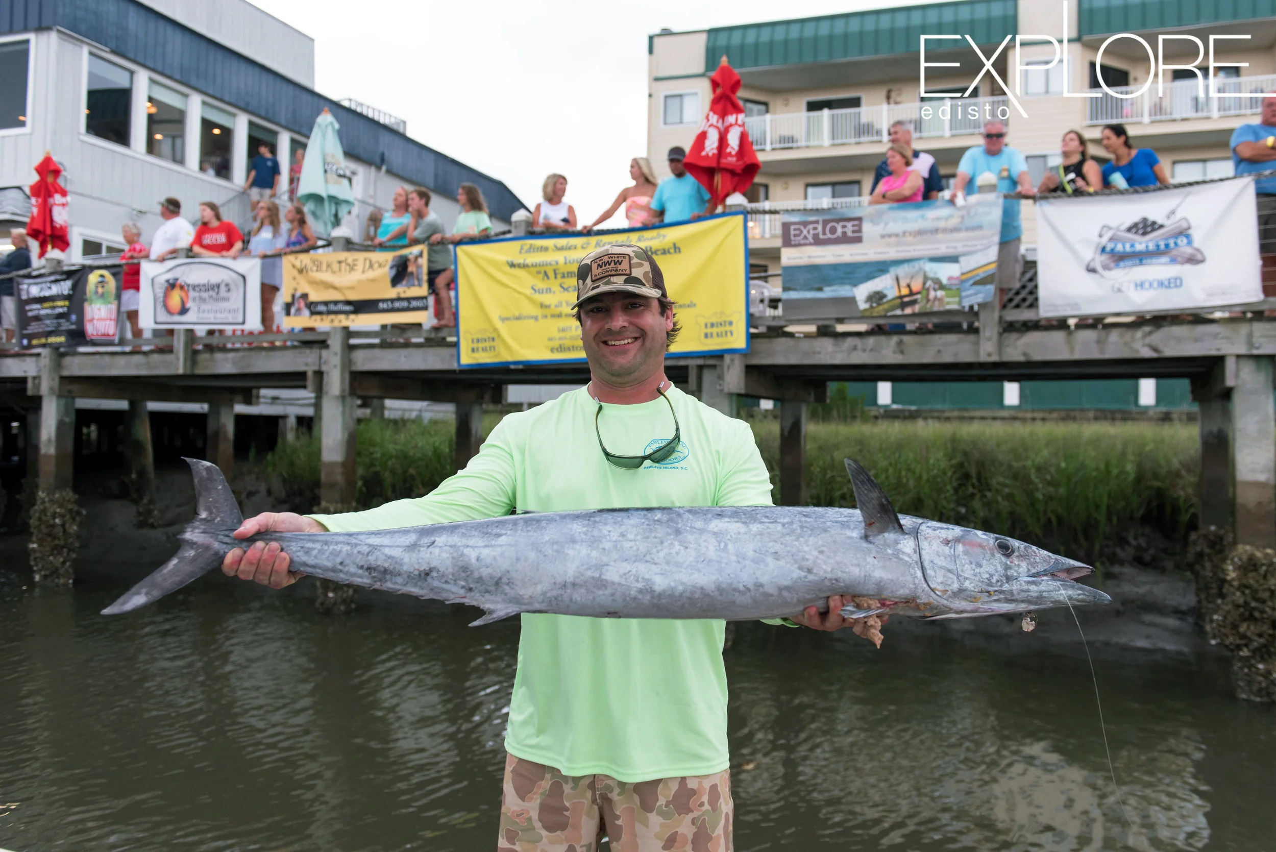 Man in green shirt and hat poses with wahoo.