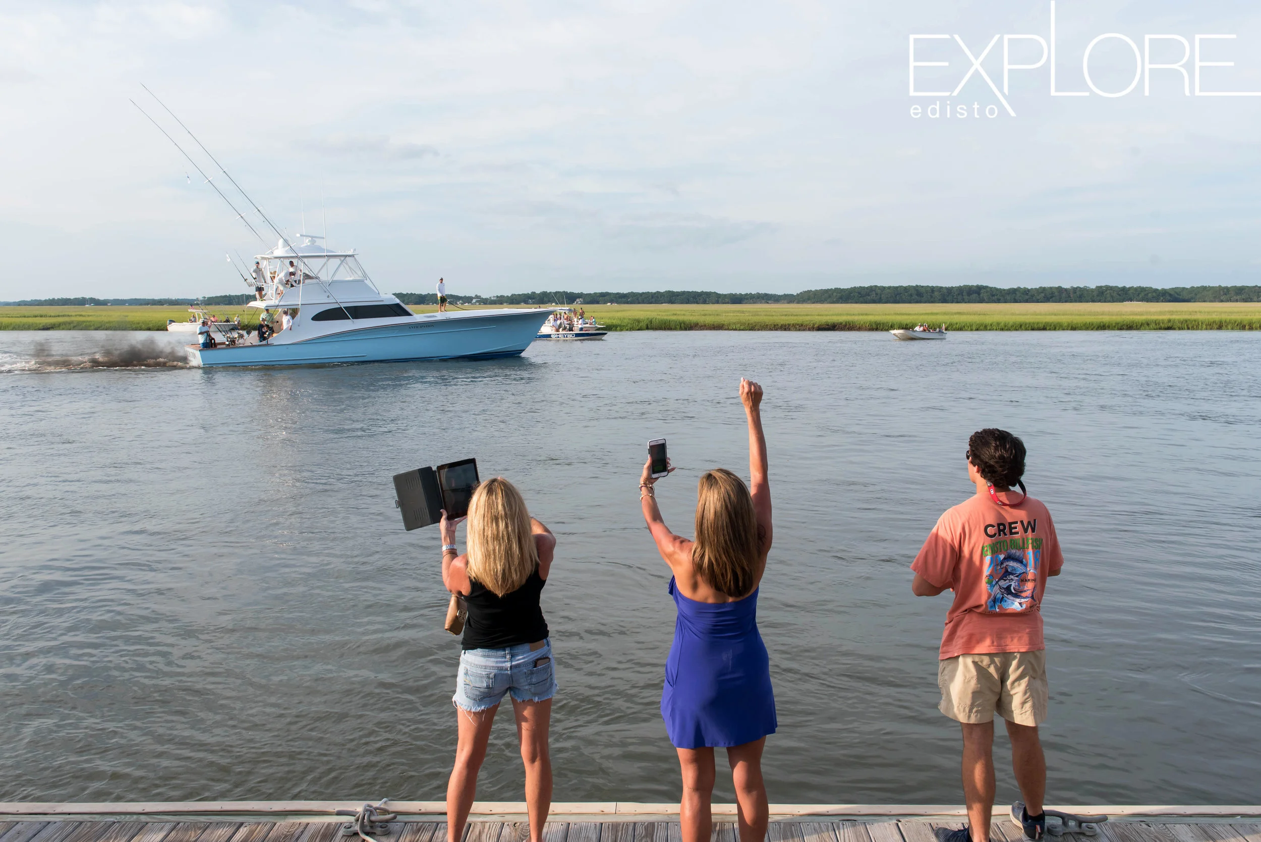 Ladies cheering and dock hand wait on boat to approach dock.