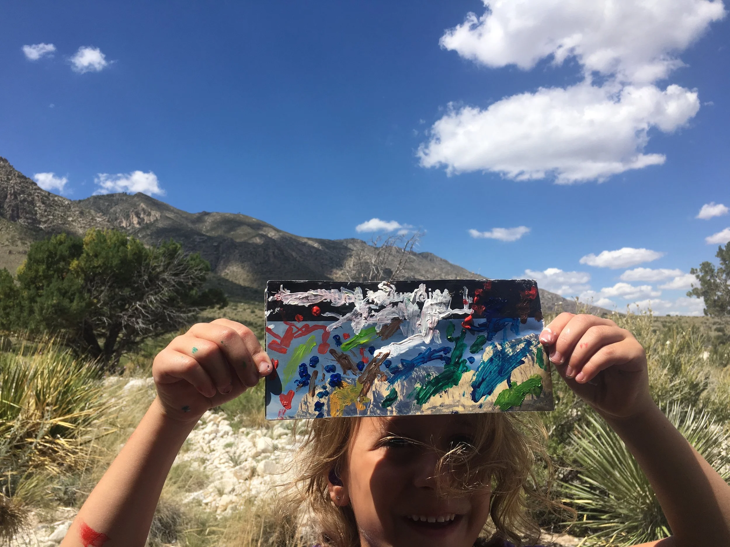Another young artist (4yo) holding up her expressive response to the landscape on a recycled map!