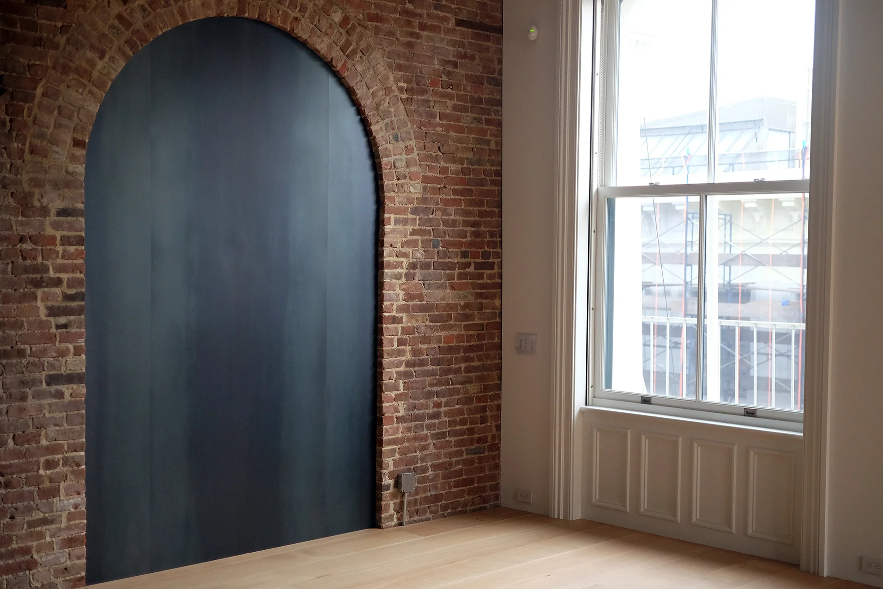  In this converted brush factory loft clear lacquered steel fills the archway in a brick wall... 