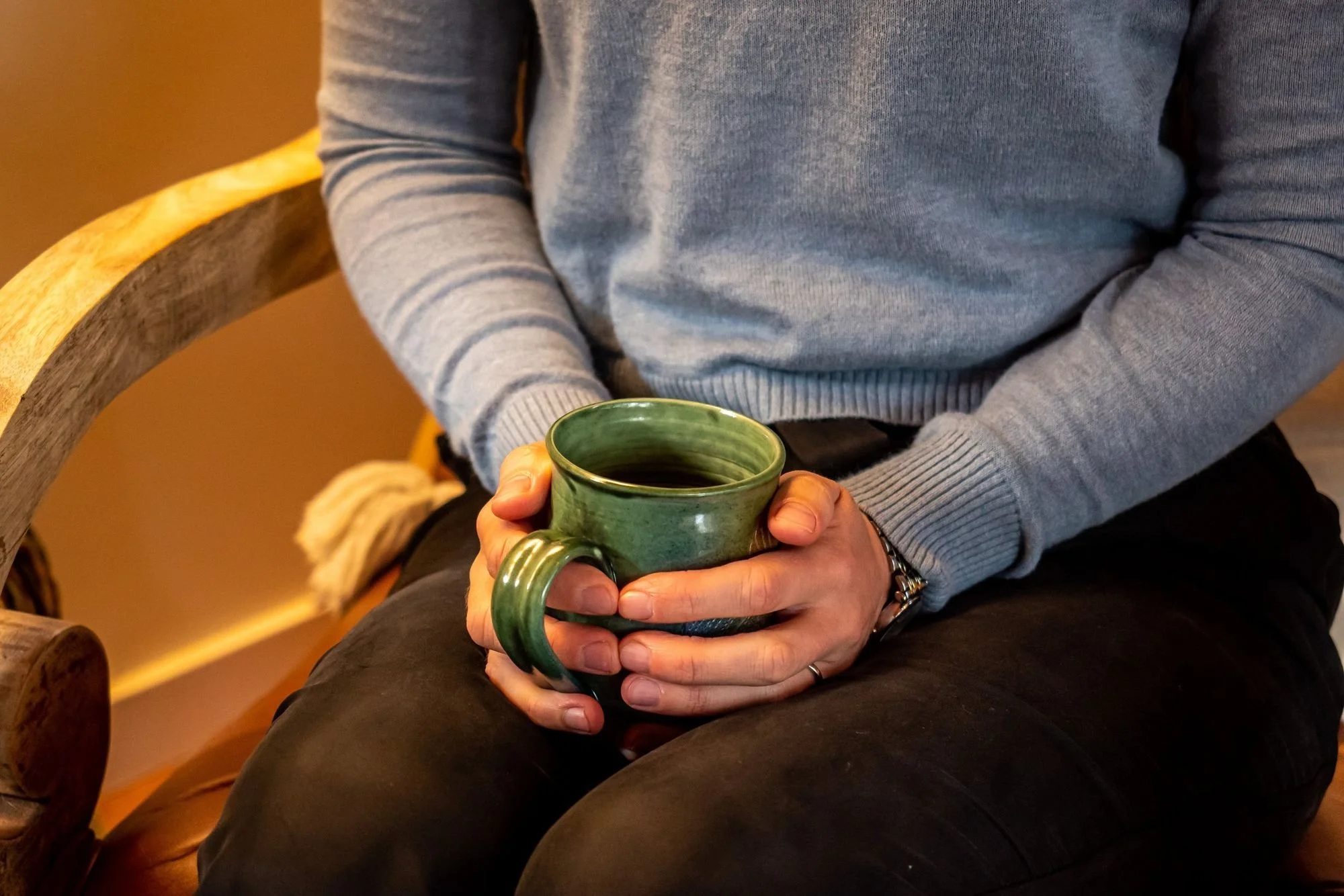 Hands holding a green ceramic mug