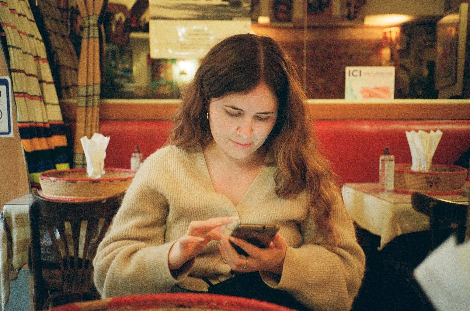 Hayley sitting in a cosy Ethiopian restaurant in Paris, looking at her phone.