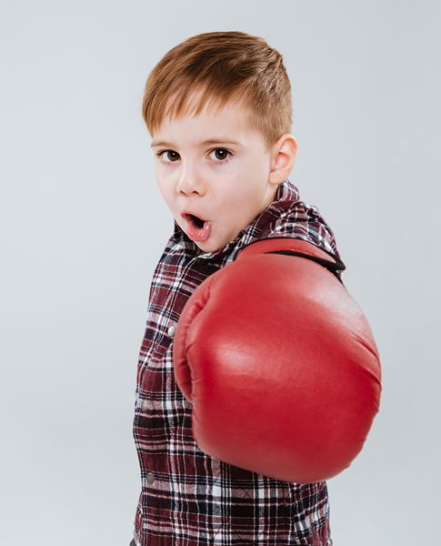Litle boy in boxing gloves standing and fighting