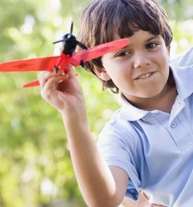 Man and young boy outdoors playing with toy airplane smiling