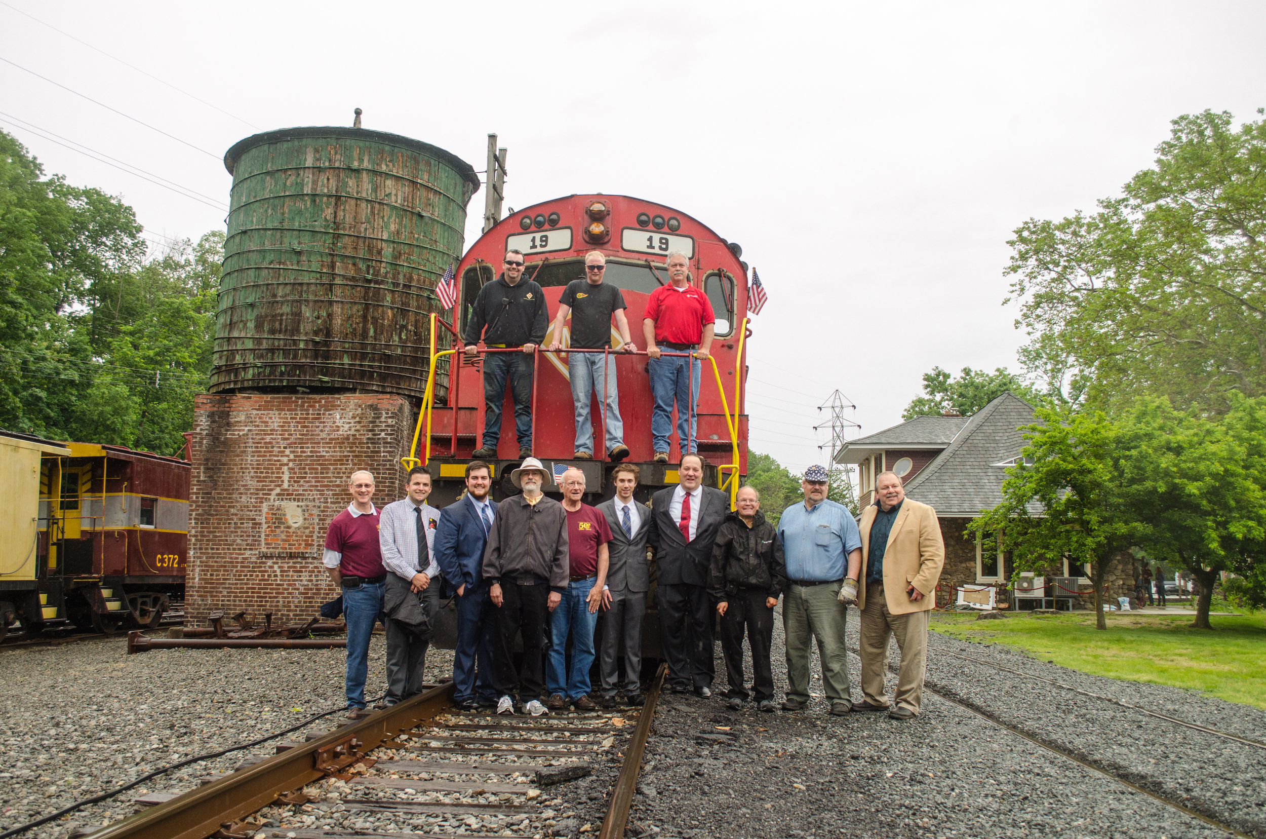  The M&amp;E crew and the Tri-State board pose in front of No. 19 at the end of the trip. 