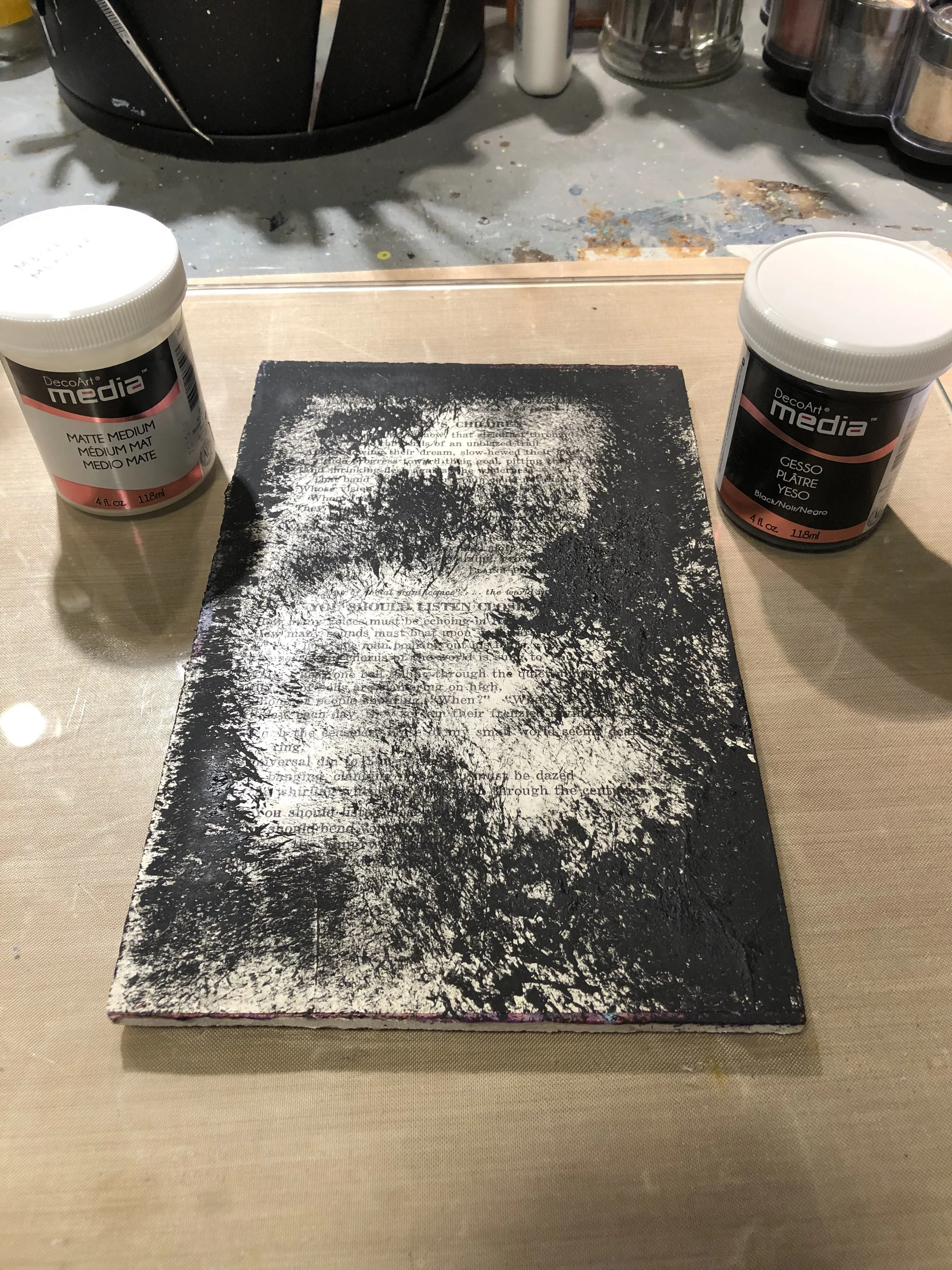 Adhere torn vintage book papers to a board or canvas using DecoArt Matte Medium. Randomly add DecoArt Black Gesso over the collaged paper.