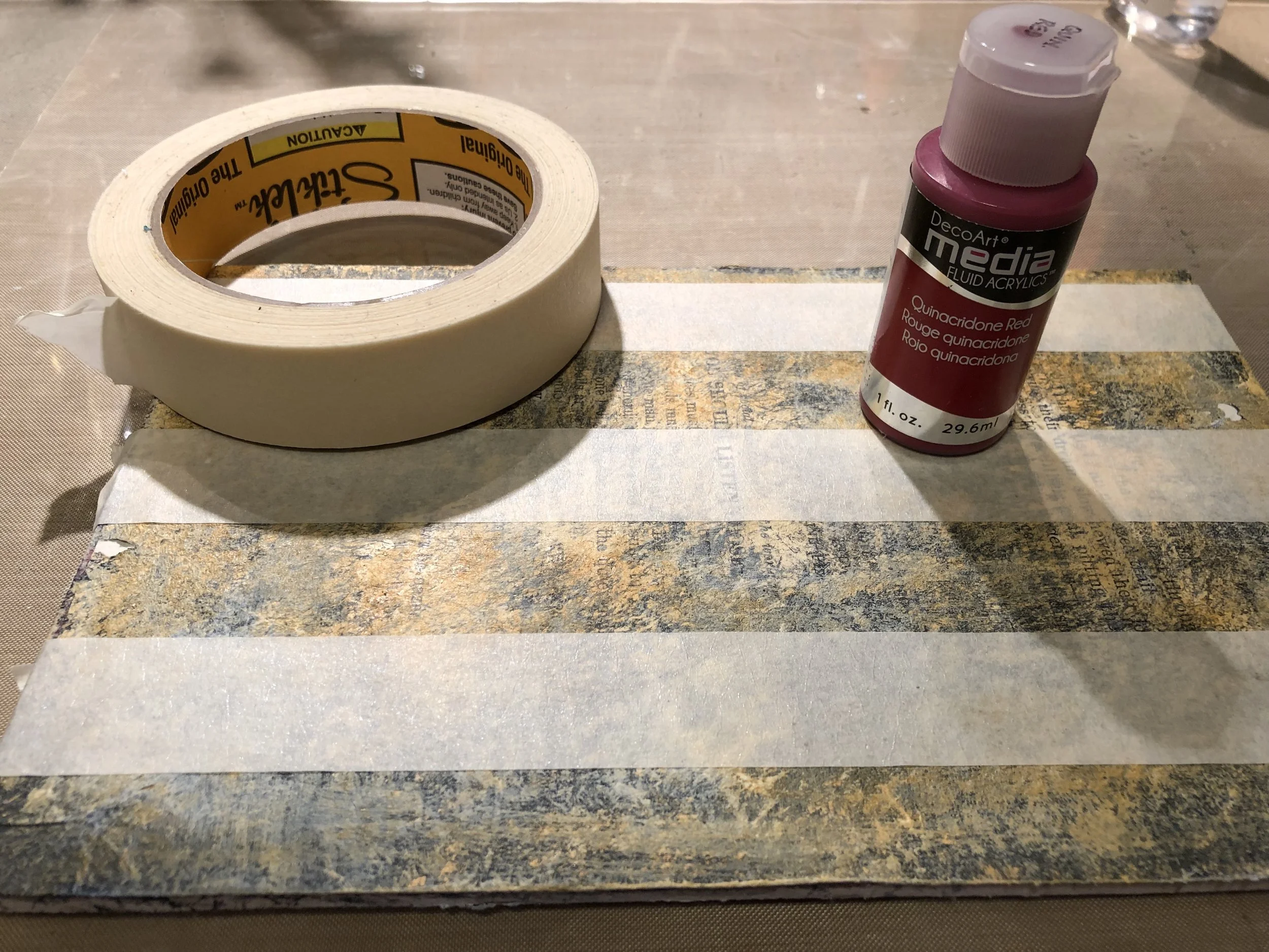 Using masking tape, block off some stripes. Then apply DecoArt Fluid Fluid Acrylic in Quinacridone Red.