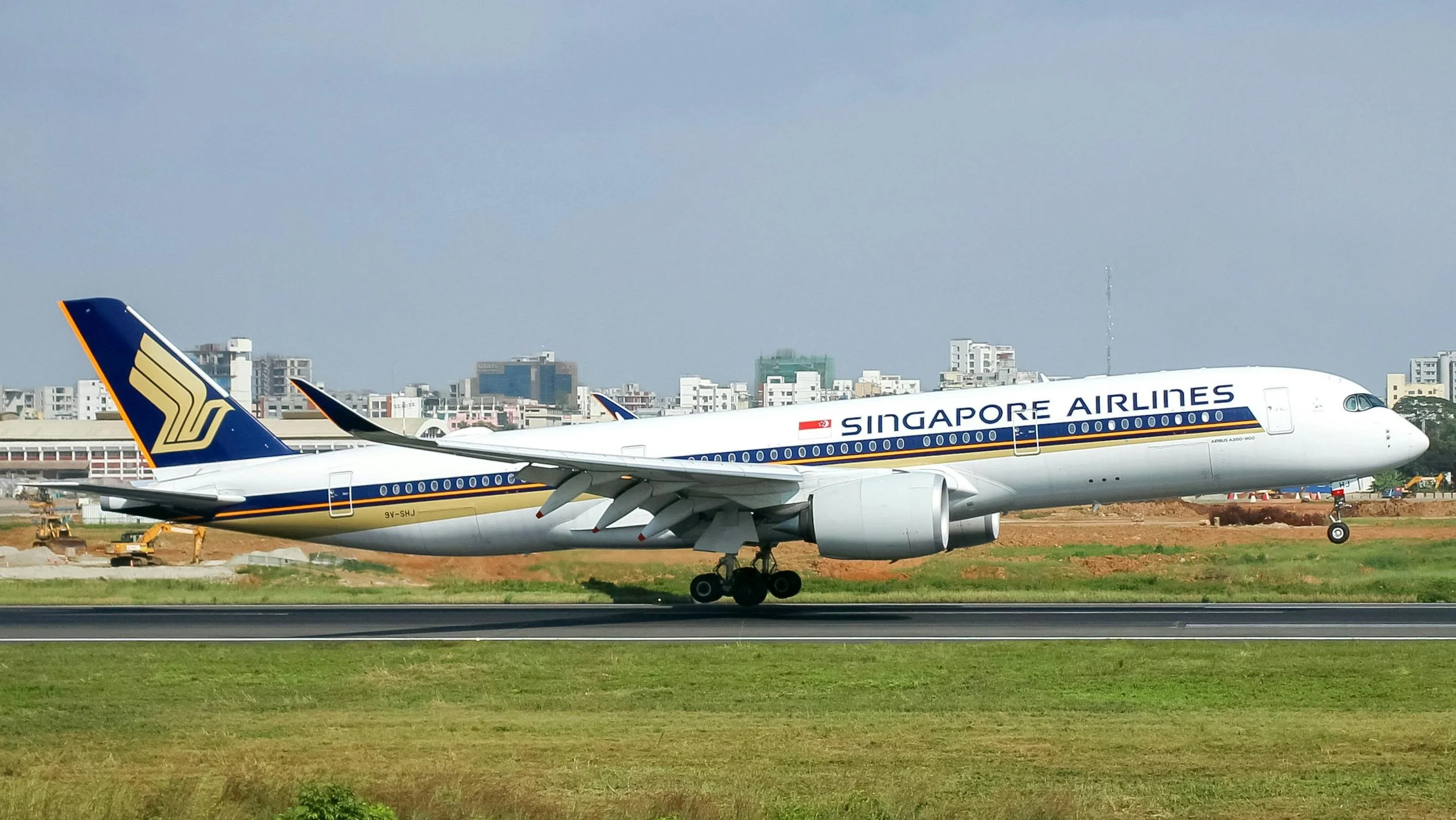 Close-up of a long, sleek Singapore Airlines passenger jet seen side-on as it takes off from a runway.
