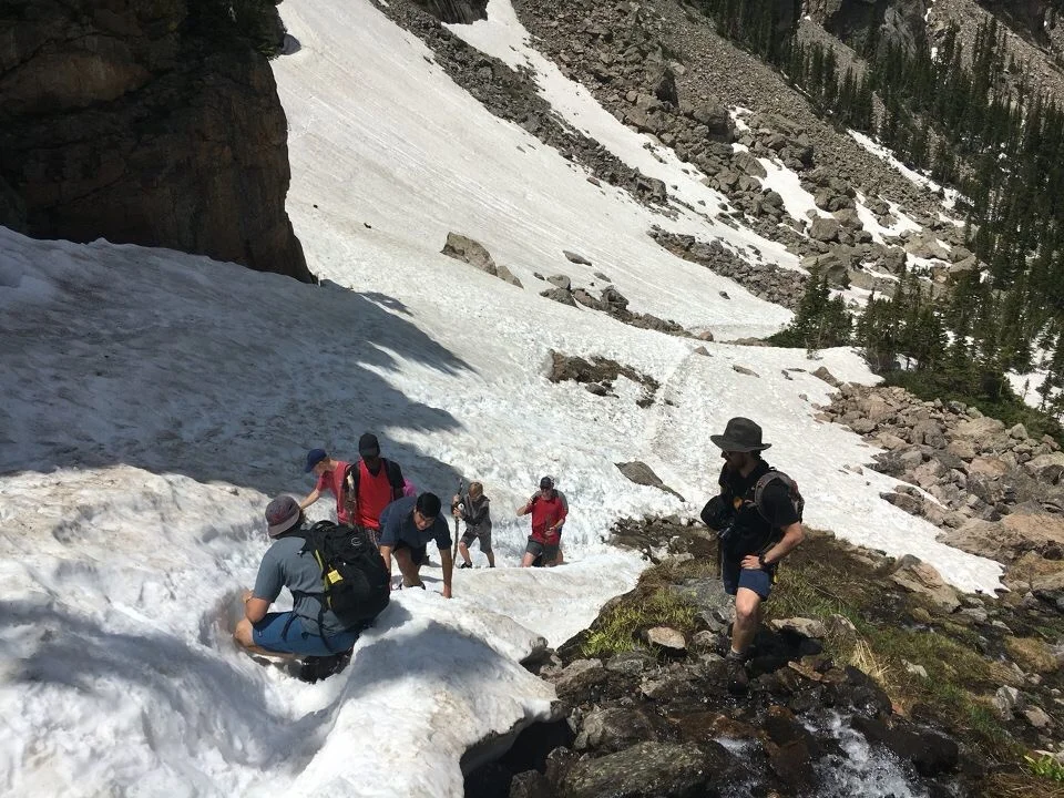 Davis & Patrick guiding kids across a snow field up to an incredible mountain waterfall.