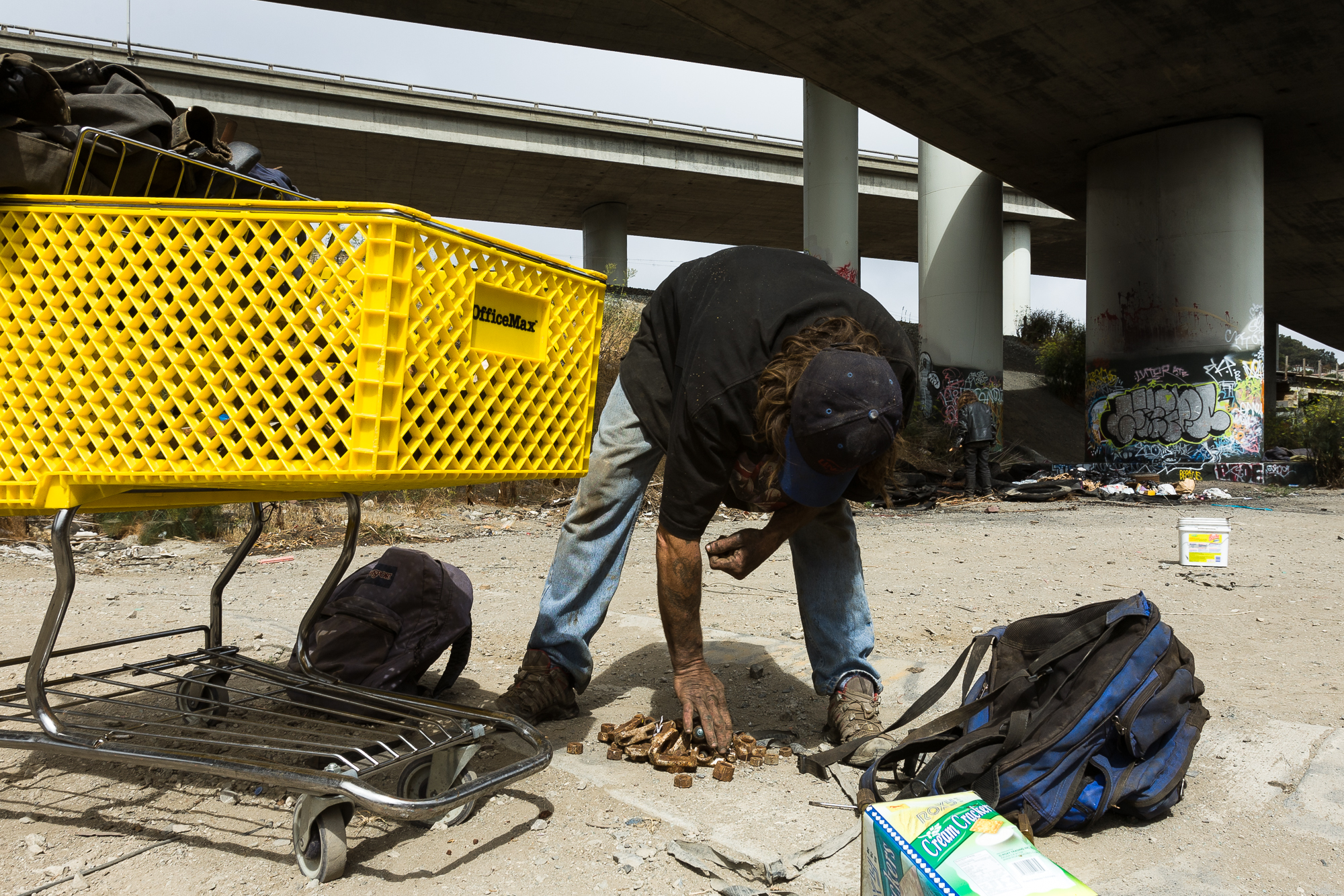  Mike sifts through the trash behind an auto wrecking yard for any type of metal the can find. With one bag already full of random scrap, Mike gathers all of the random nuts and bolts into a pile while his partner looks through the remnants of burnt 