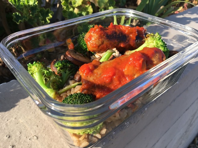 Tofurkey sausage marinaded in tomato sauce over brown rice and vegetables
