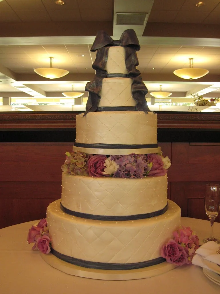 This large wedding cake was detailed in a quilted pattern in fondant with painted navy bands and bow. The quilted look does look best in fondant.
