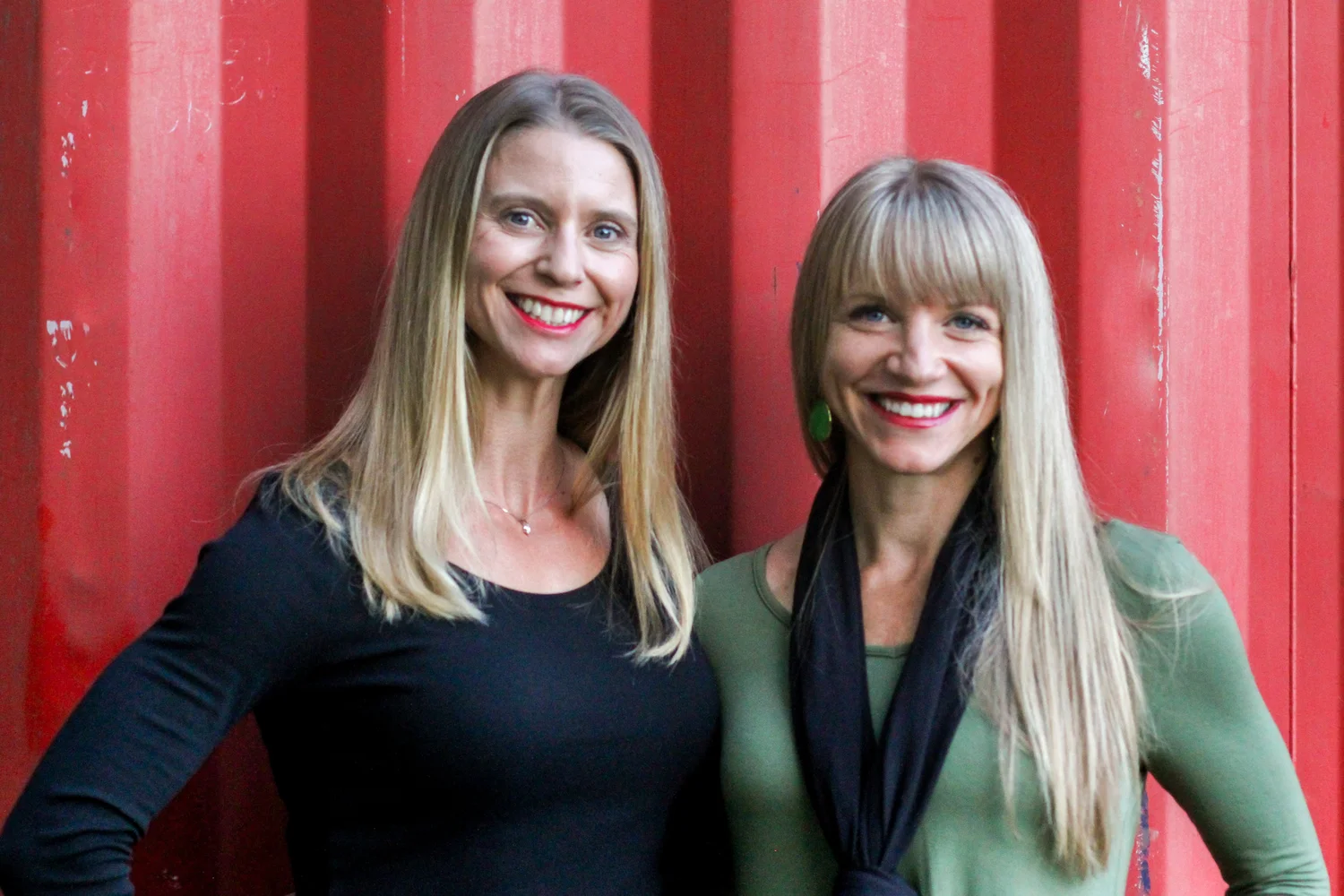 Shelly Iverson and Shelly Begines of Team Shelly, smiling in front of a red wall