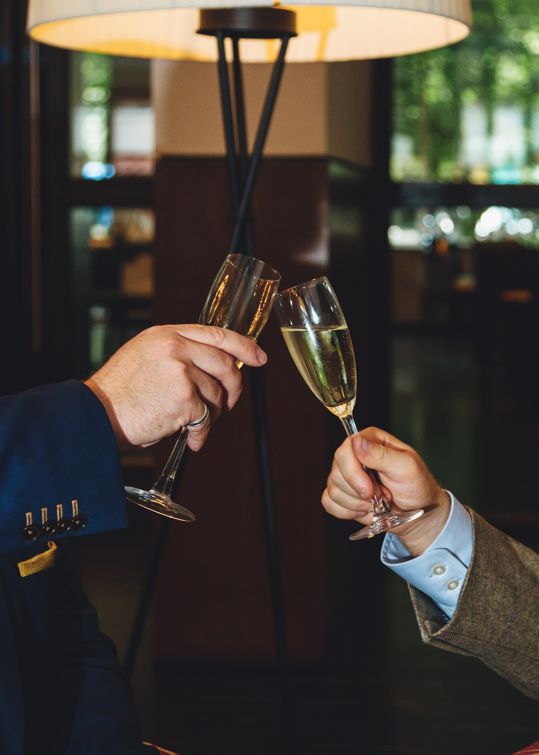 clinking champagne glasses following 2 grooms getting married at Park Plaza Hotel Cardiff with gay friendly south wales wedding photographer