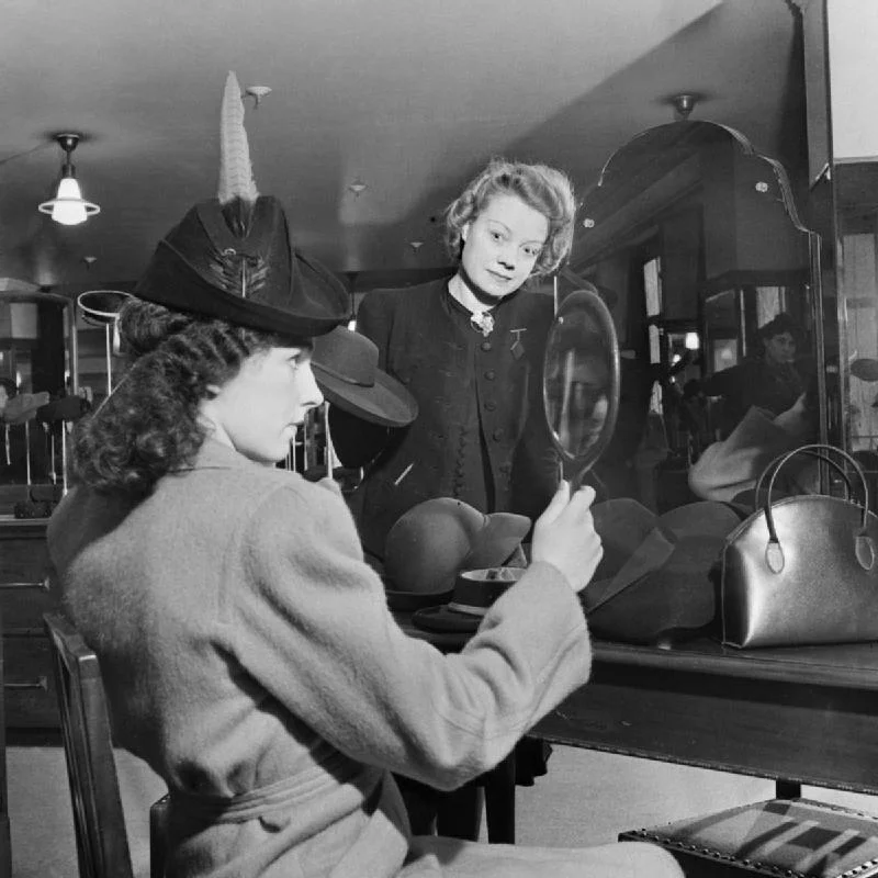 A customer tries on a new hat in the millinery department of Bourne and Hollingsworth on London's Oxford Street in 1942
