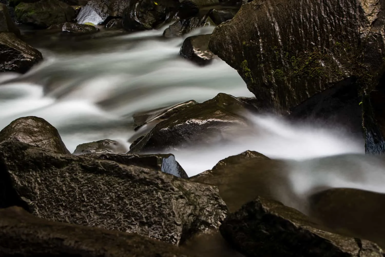 The river fed by the La Fortuna Waterfall flows over rocks into a lagoon.