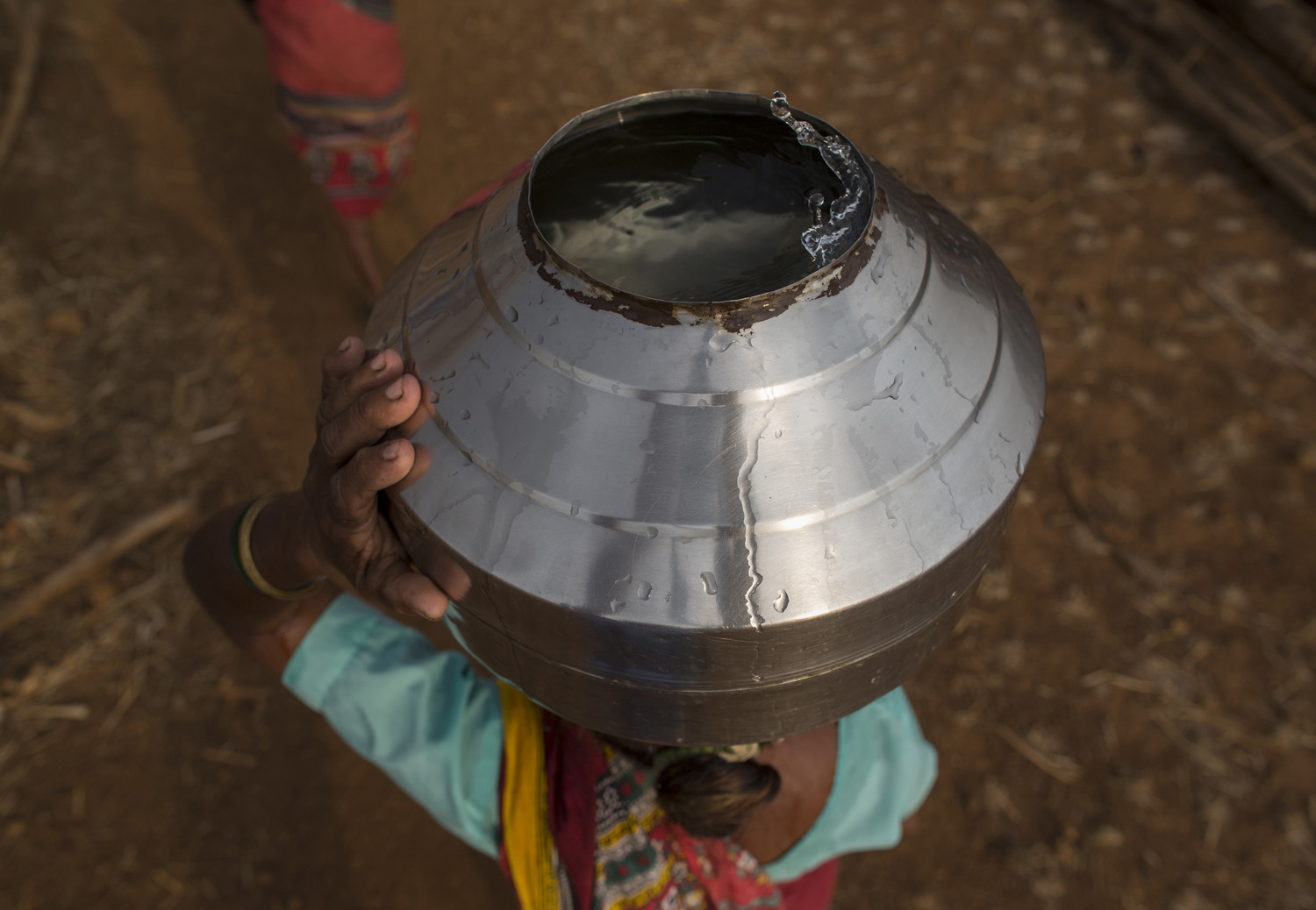  Bhaagi, third wife of Sakharam Bhagat, carries a metal pitcher filled with water from a well outside Denganmal village. 