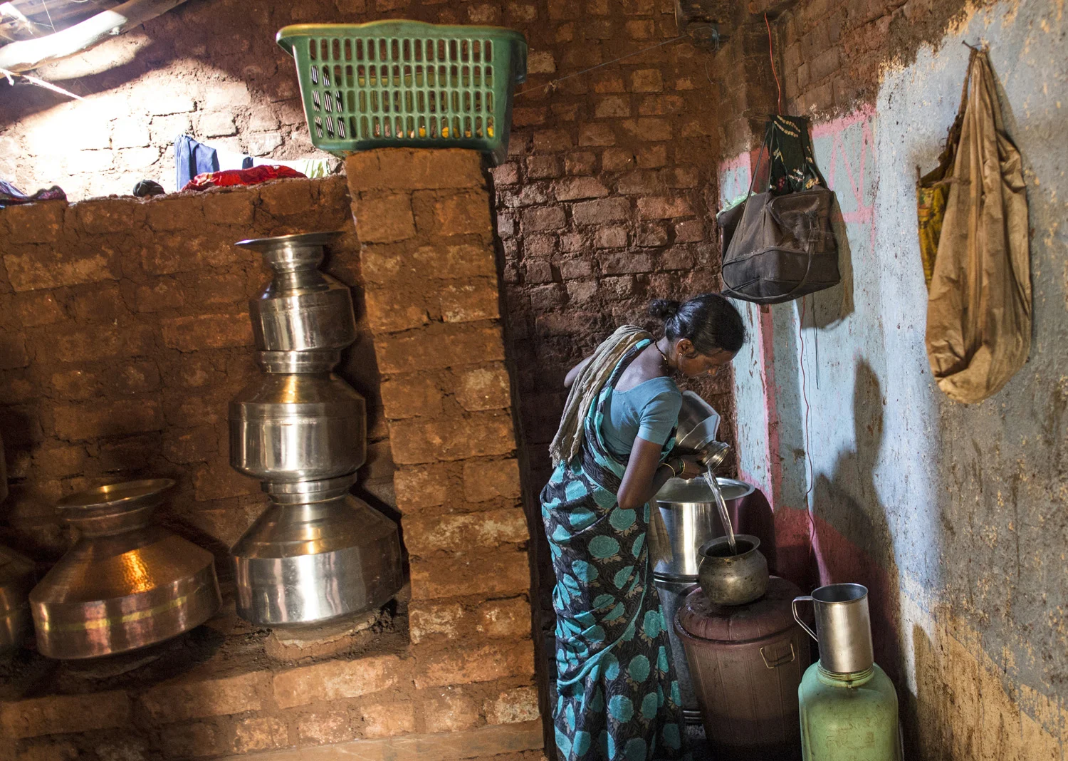 Shivarti, second wife of Namdeo, empties a water pitcher as she gets ready to fill water from a well outside Denganmal village.