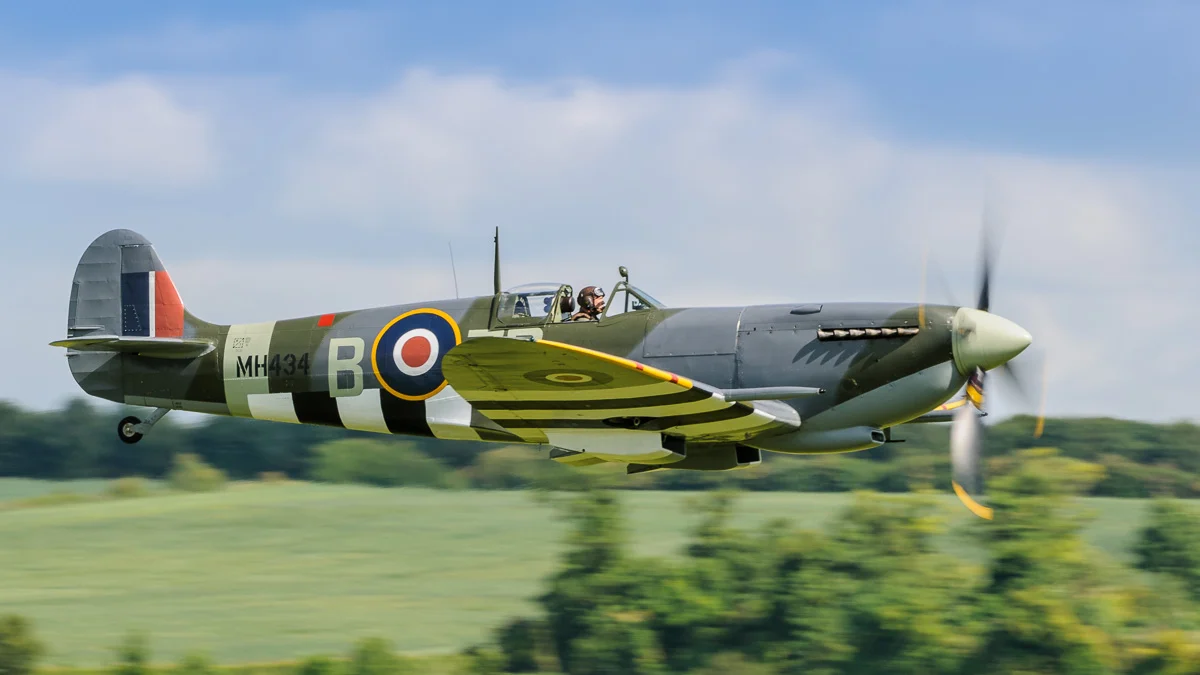 Spitfire MH434, keeping low after taking off. The aircraft is moving quite fast, so a moderate shutter speed helps convey movement by blurring the background, and revealing propeller movement. Nikon D300, Nikon 200-400mm f/4G VR II, 1/250 sec, f/8, ISO 200, 350 mm