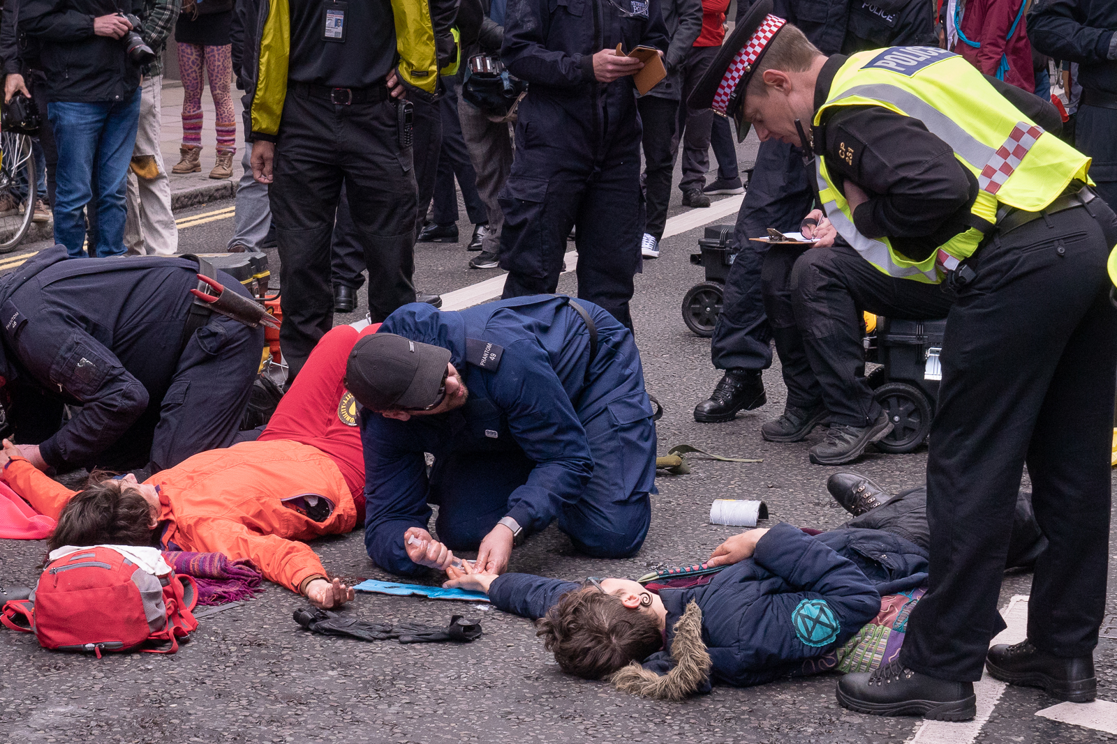 Applying a solvent to a protestor, a member of the police unglues a hand