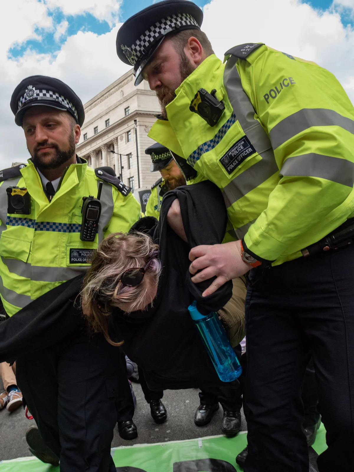 A protestor is removed, re-usable water flask in hand