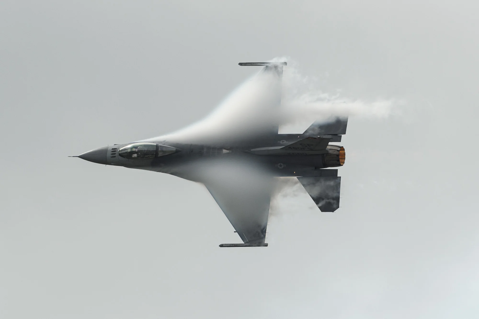USAF F-16, afterburner on, creating its own clouds as it pulls a high-G turn under the low cloudbase