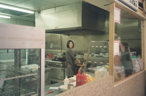 my cousin in the kitchen of her convenience store frying chicken