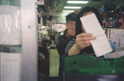 my tired father behind my mother behind a lotto machine behind a dirty plastic wall