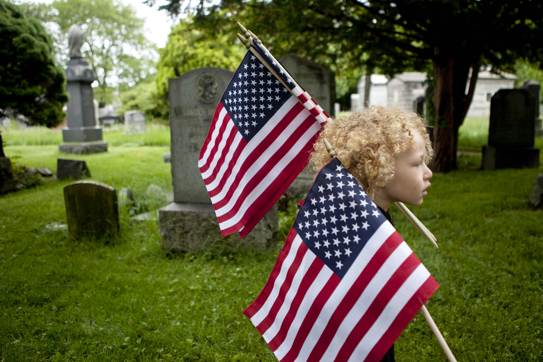 Jahvanni Gifford, 4, carries flags to place at veteran’s graves on Memorial Day at Bayview Cemetery in Jersey City. Roughly a dozen service members and thirty children representing various scout troops came together to honor the veterans.