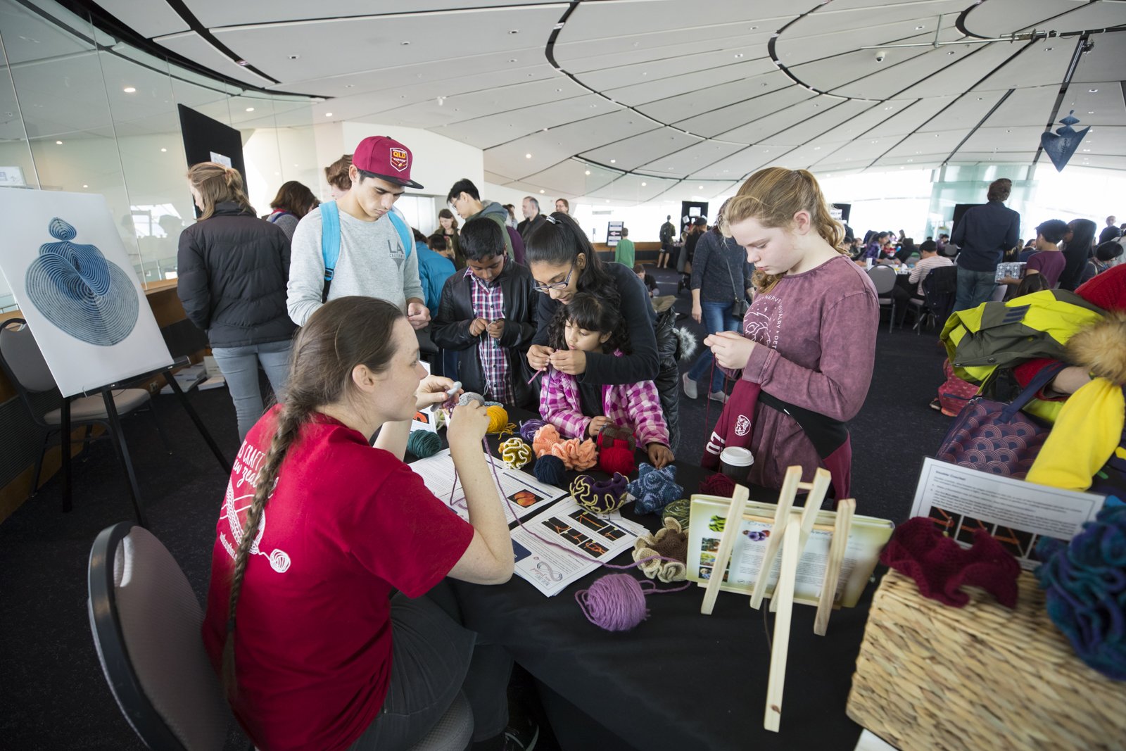 Visitors and a volunteer at the crochet station at the Maths Craft Festival