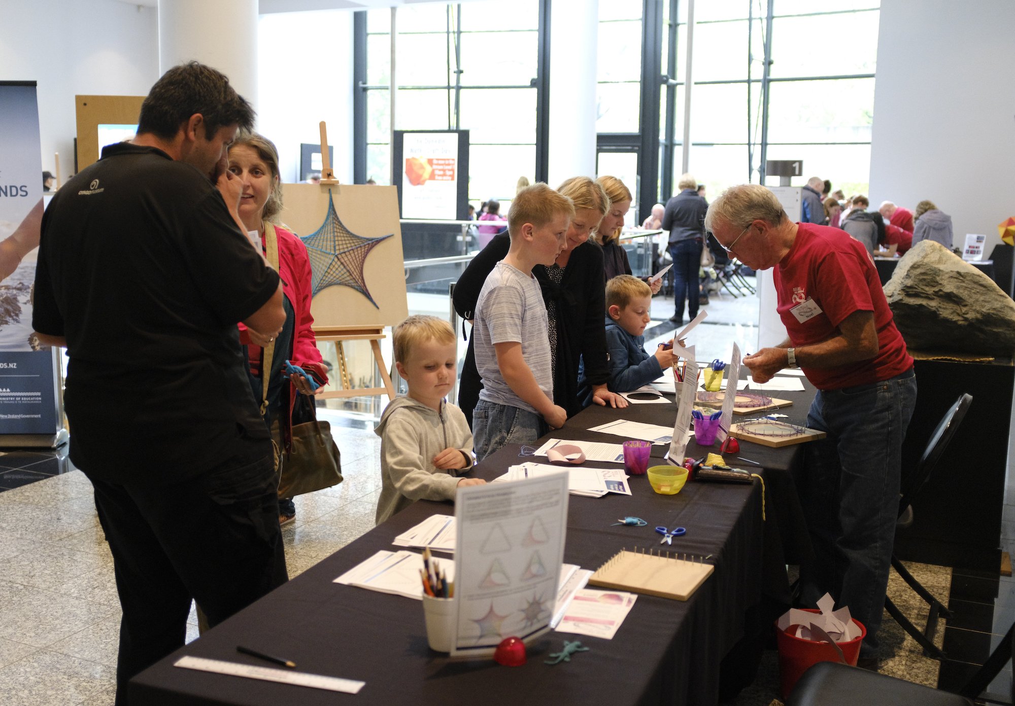 Visitors and a volunteer at the string art station at the Dunedin Maths Craft Day