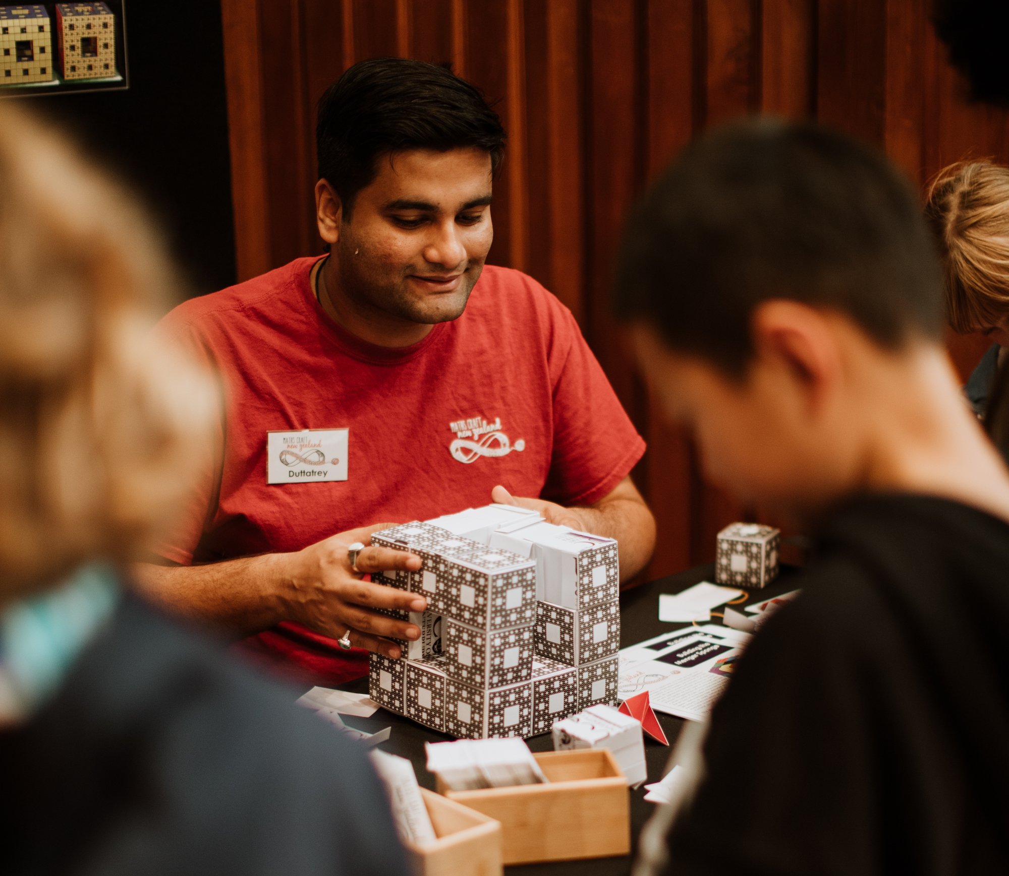 A volunteer helping visitors build Menger sponge sculptures at a Maths Craft event (Copy)