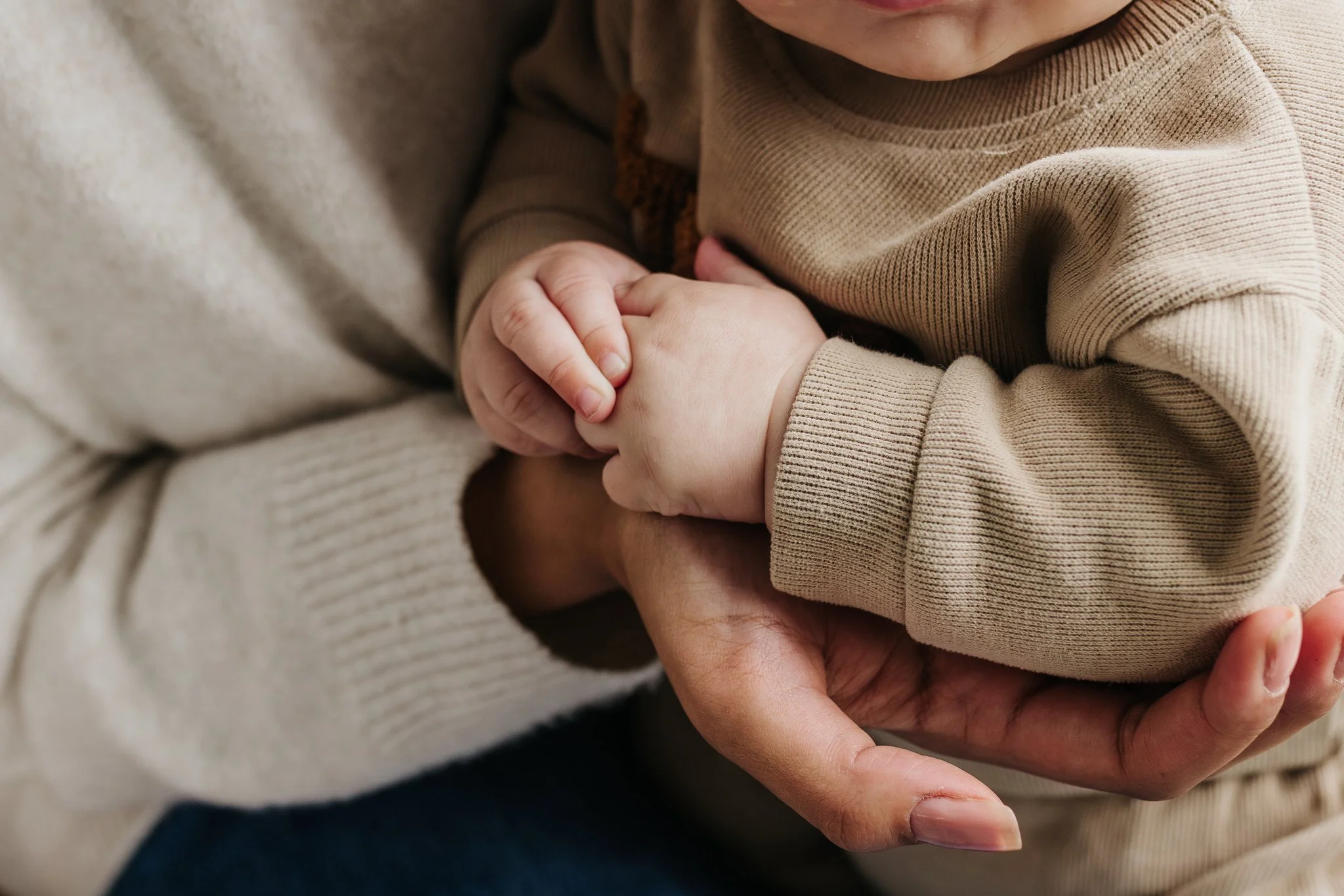 A close up of a woman's hand and baby's hands.
