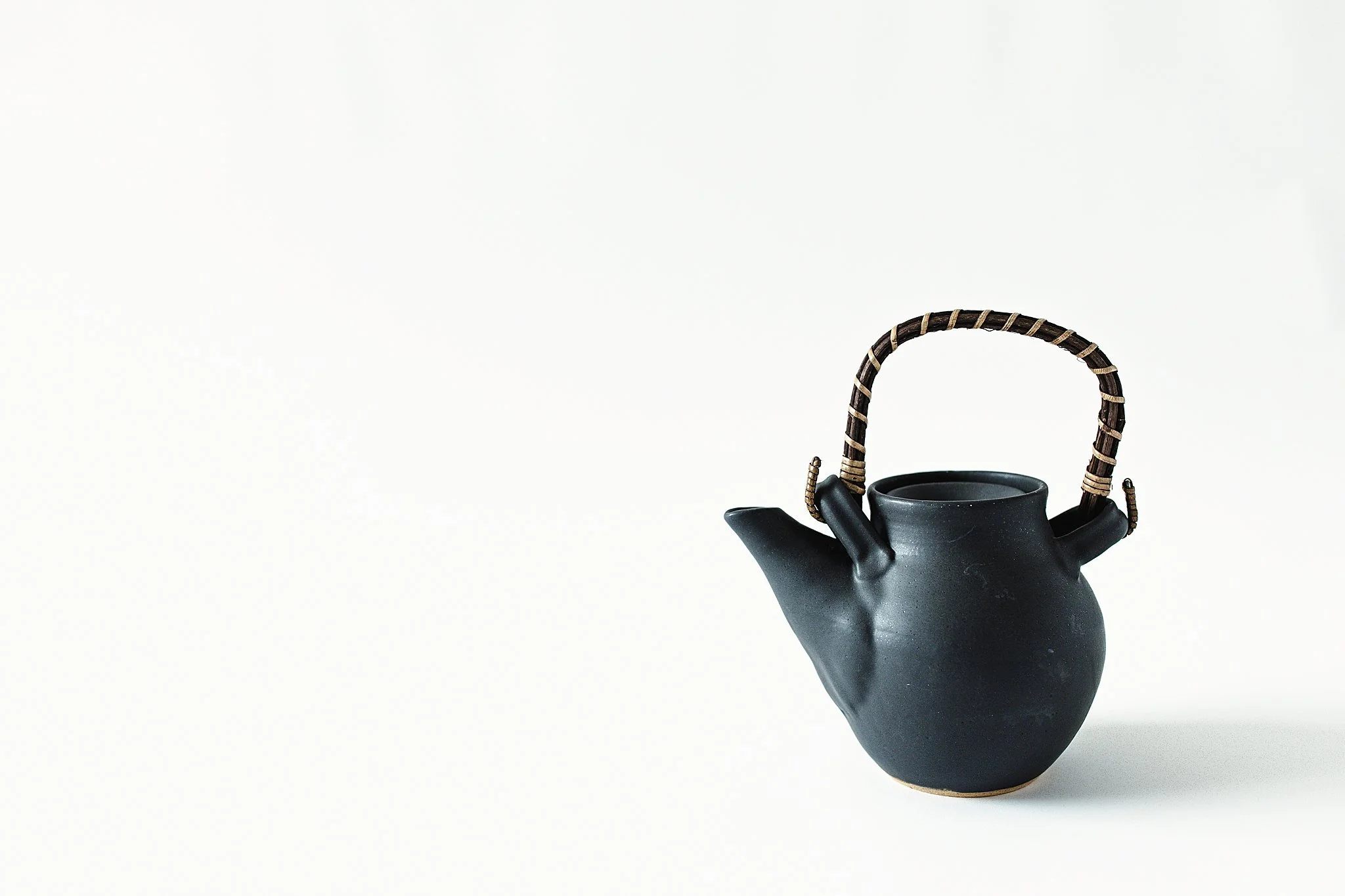 Black teapot with bamboo handle on white background for small business product photography Naperville, IL.