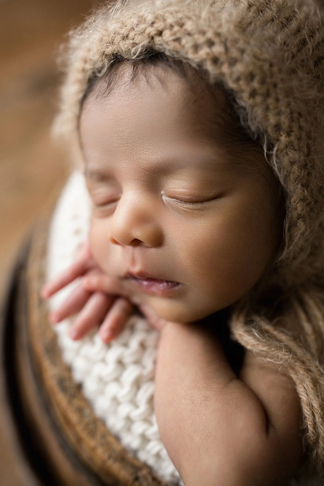 A close-up of a sleeping baby wearing a knitted hat, peacefully resting with hands under her chin during newborn photography Naperville.