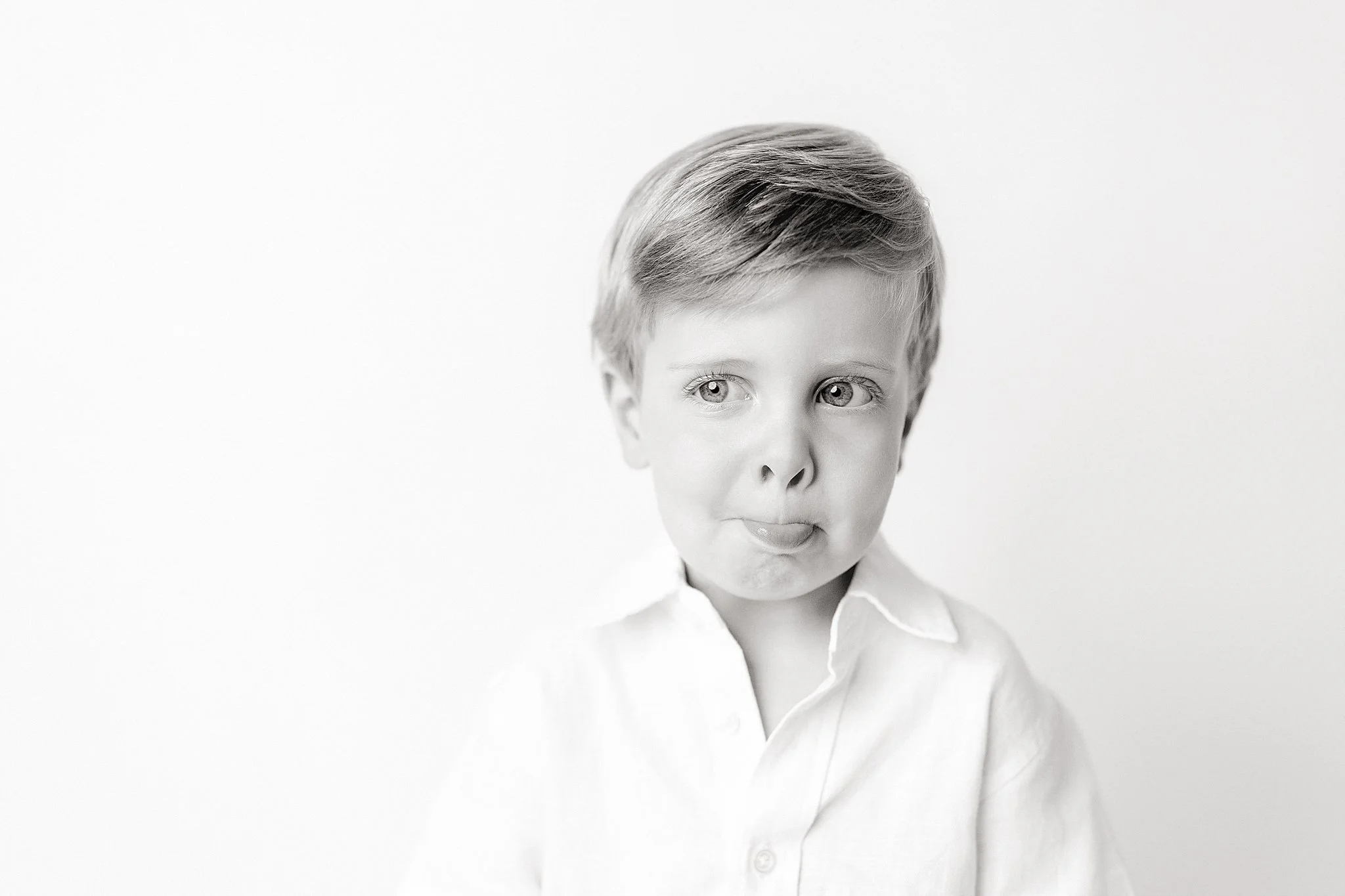 Black and white portrait of a young boy with neatly styled hair, wearing a collared shirt, looking slightly to the side, with a neutral expression during a personality mini session in Naperville, IL.