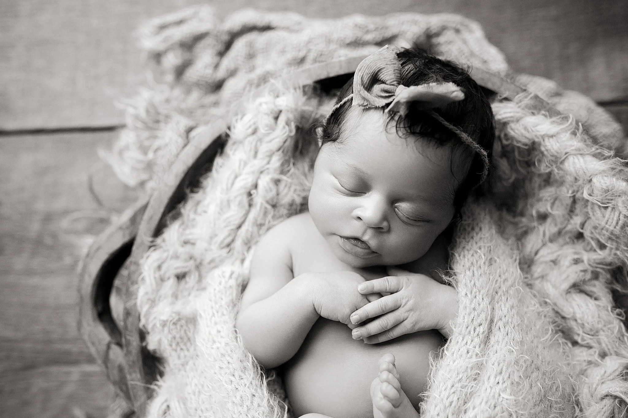A sleeping baby with dark hair, wrapped in a cozy blanket and a soft, fuzzy blanket surrounding them during photos with a Naperville newborn photographer.