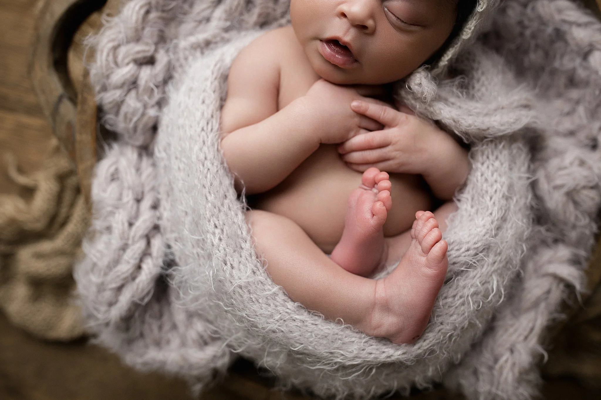 Close-up of a sleeping baby with dark skin, wrapped in a soft, fuzzy blanket, resting peacefully during newborn photography sessions near me.